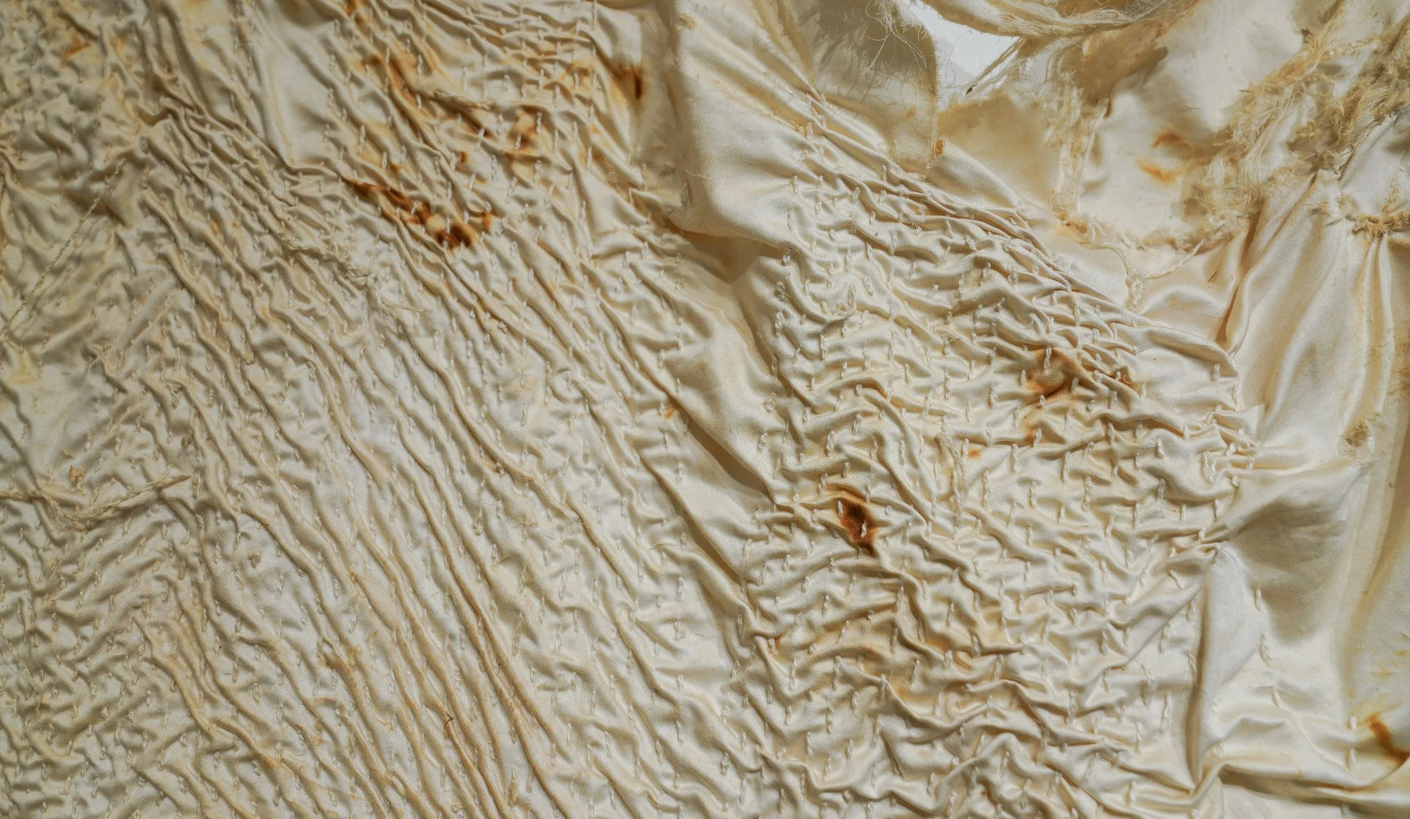 Cream-colored fabric with textured, uneven drizzles of a caramel-colored sauce.