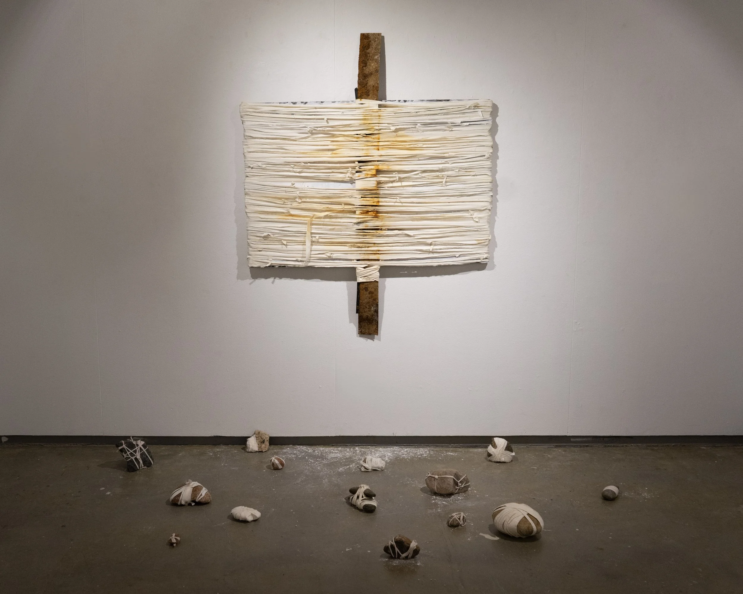 CARE, 2025 - 
bedsheets, clothing, wooden board, rusted metal, rocks
