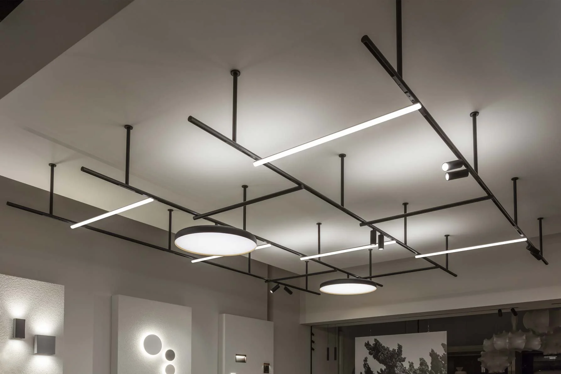 Modern ceiling lights with geometric black metal framework, including linear, circular, and cylindrical fixtures.