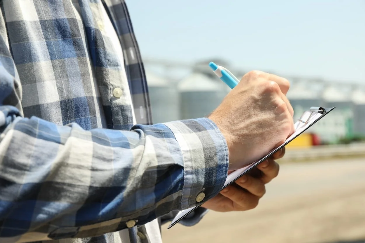 Person writing on a clipboard at an outdoor facility