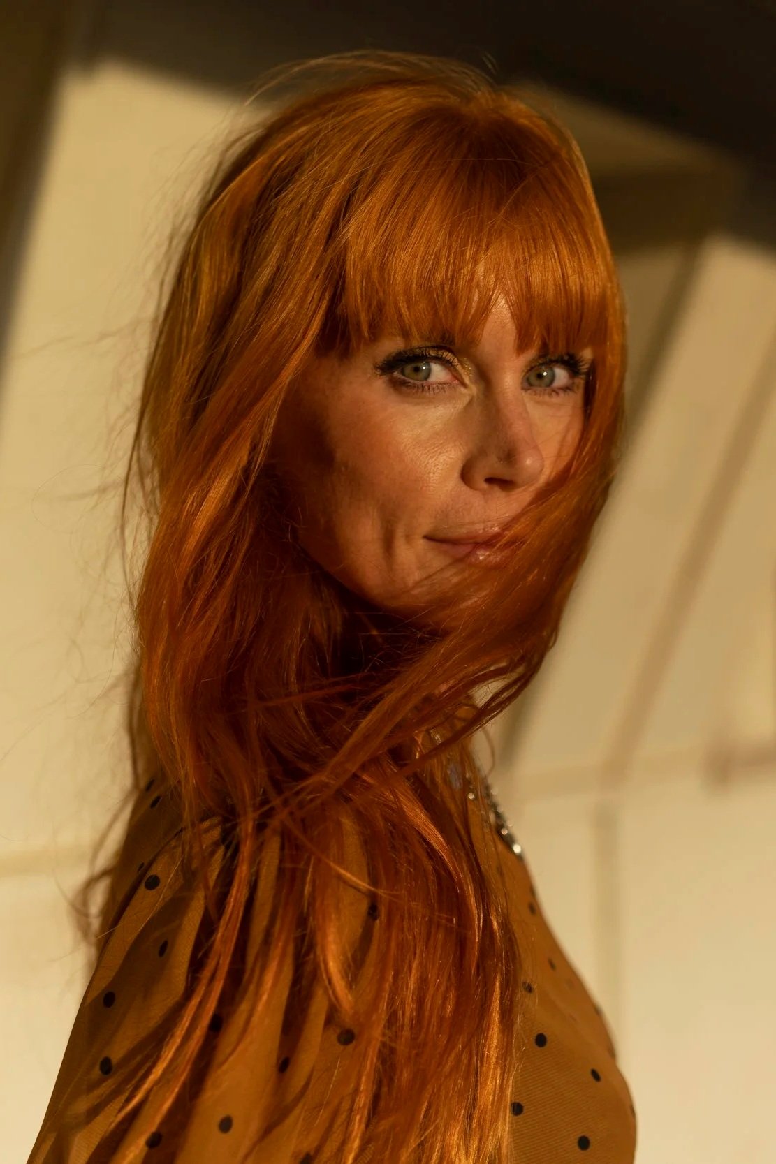 New Zealand actor Michelle Blundell photographed by Emma Cosgrave. She is looking to camera with a warm smile and long red hair