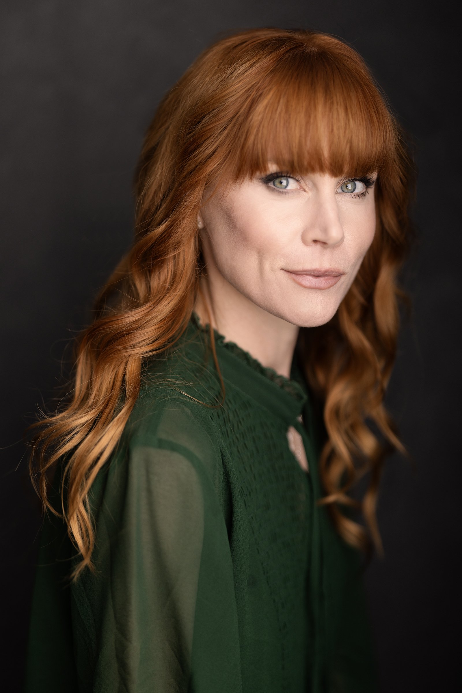 Headshot of actor Michelle Blundell taken by Andi Crown Photography. Michelle has red hair and a green top. She is looking directly to camera.