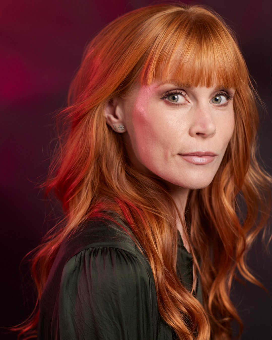 New Zealand actor Michelle Blundell photographed by Dean O'Gorman. She has red hair and a green shirt, she is looking to camera