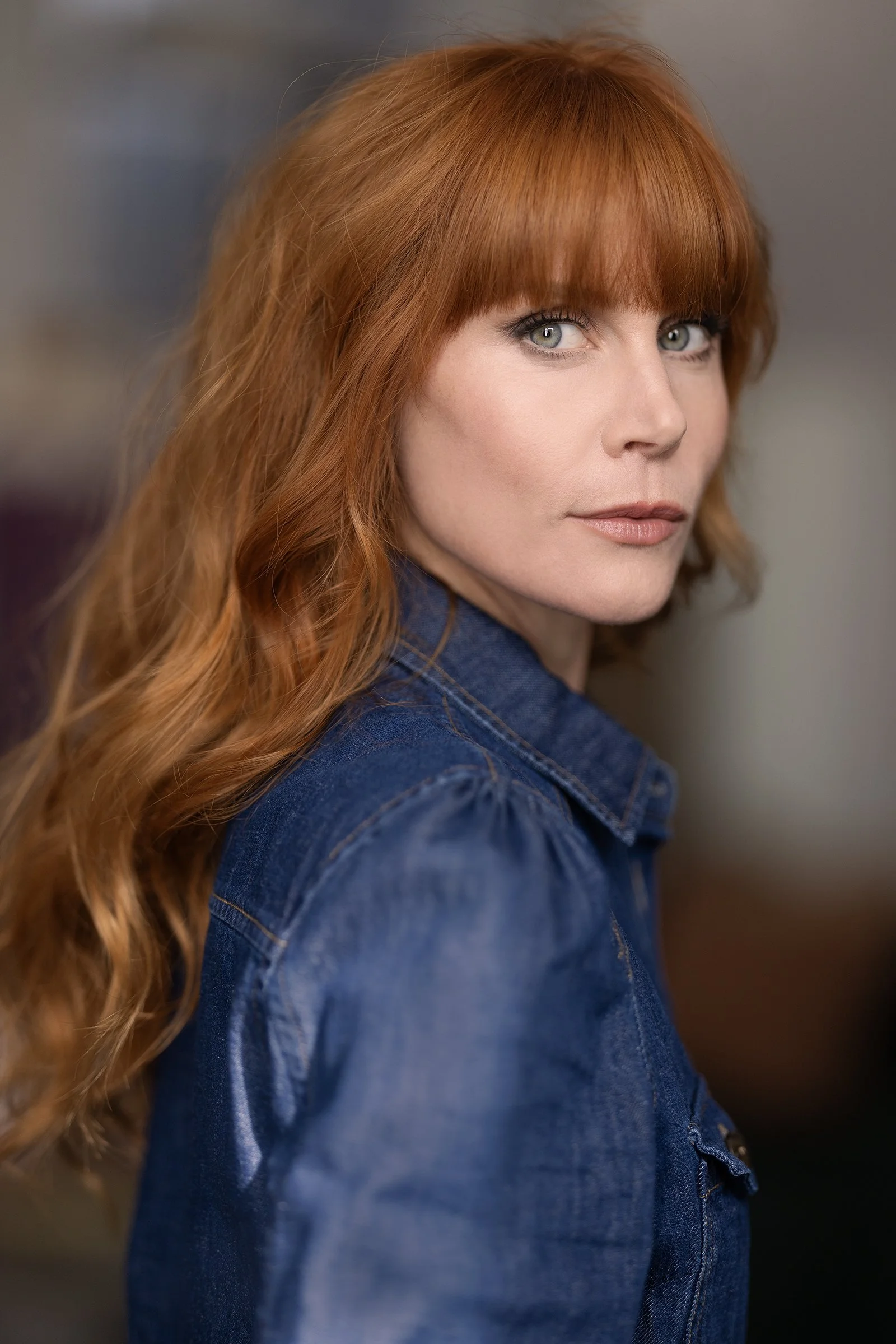 A side angle photograph of Michelle Blundell taken by Andi Crown. Michelle has curly red hair and a blue denim shirt