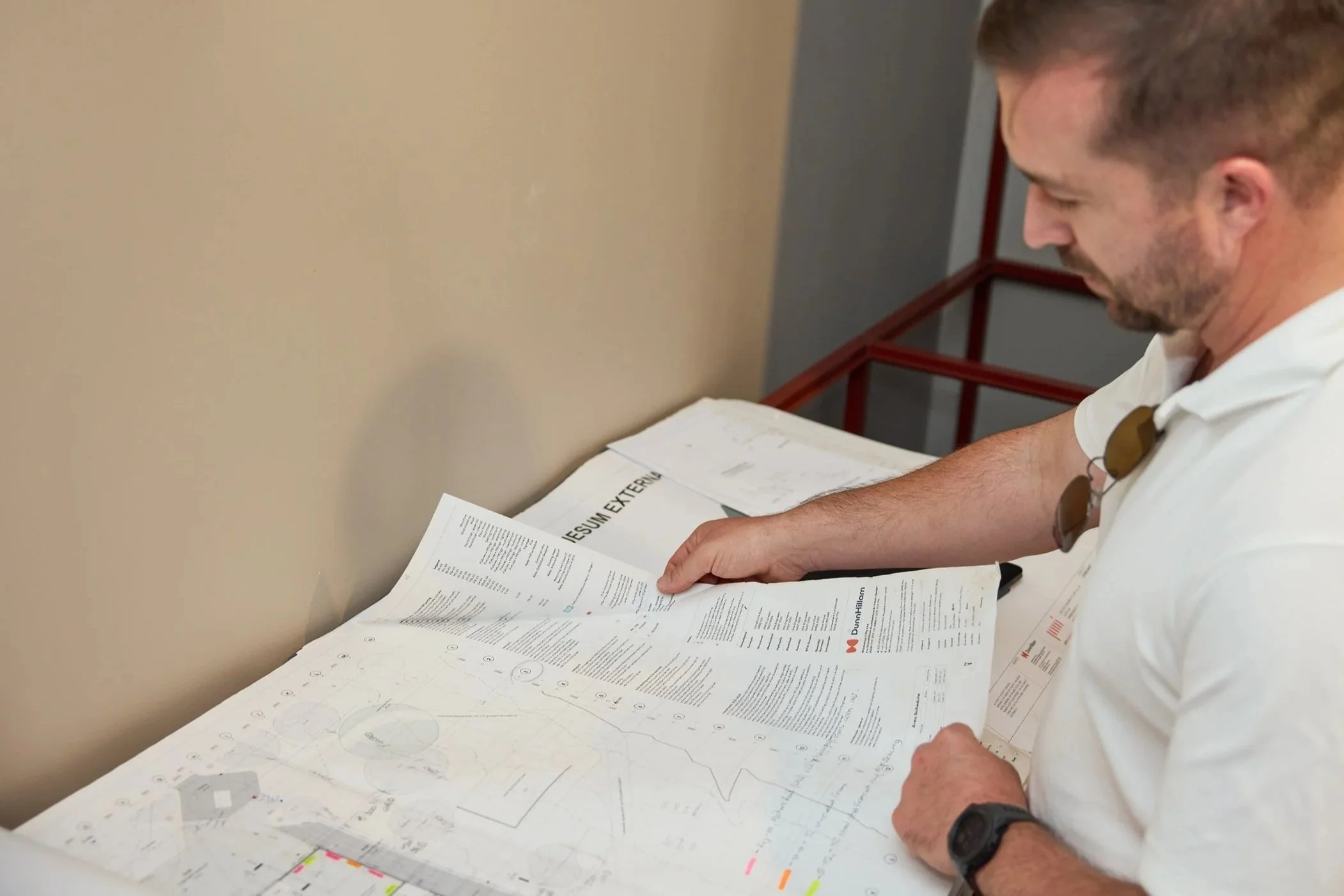 A man reviewing architectural plans and documents on a table.