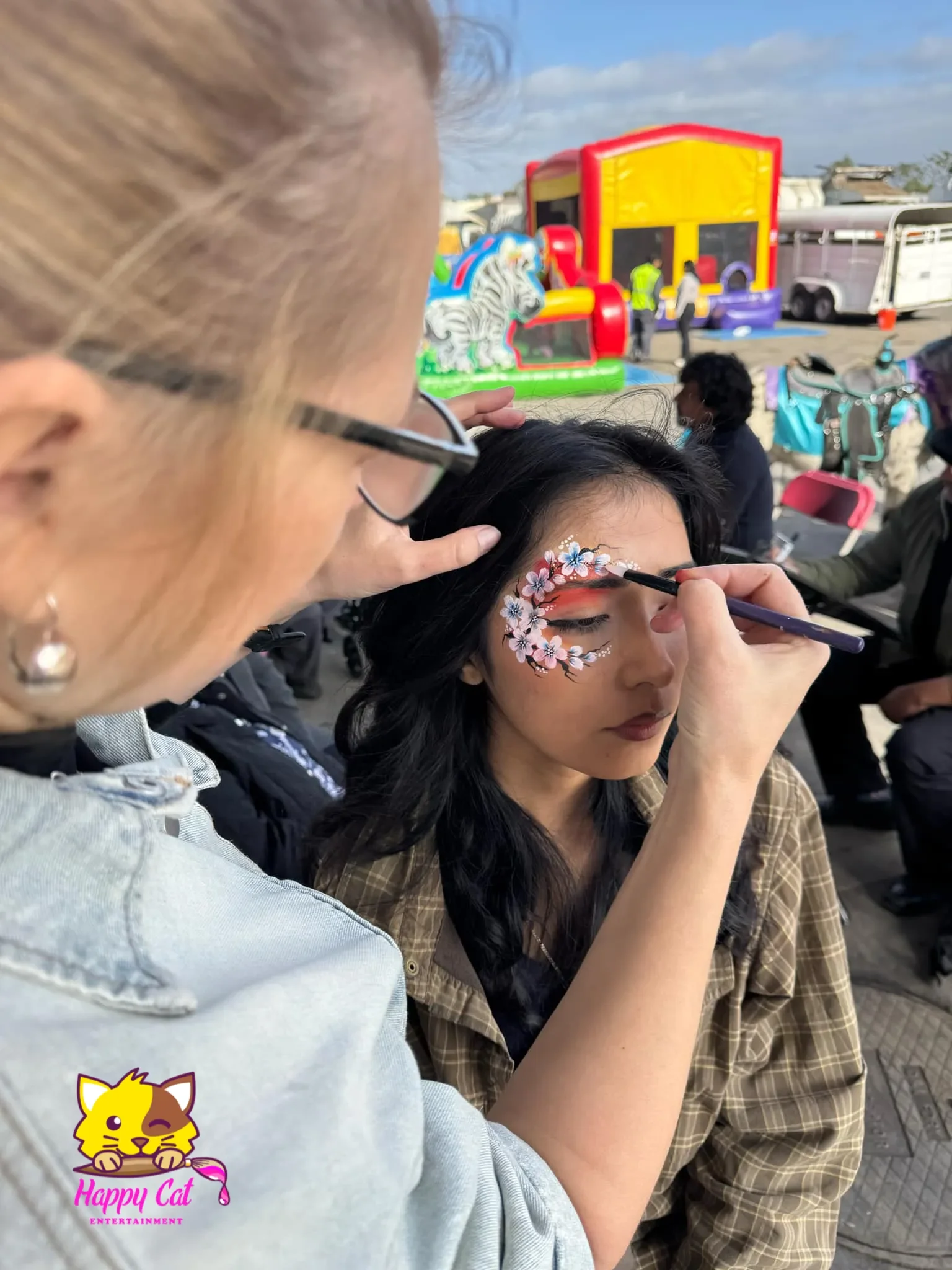 Tatiana painting a girl with a blossom face painting design by Happy Cat Entertainment