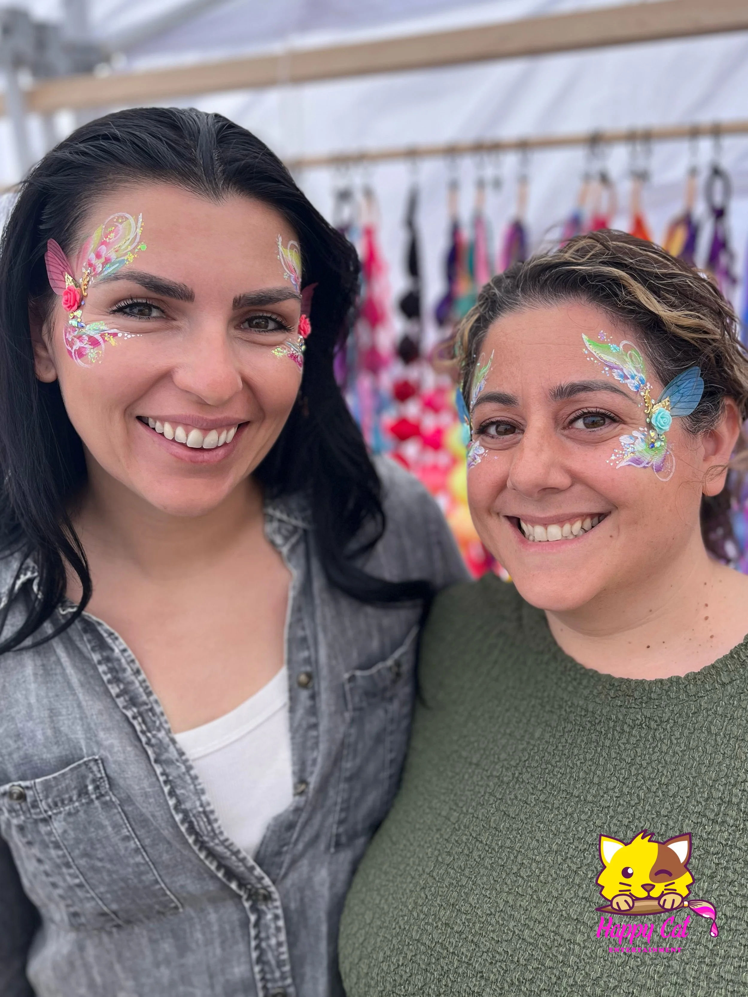 Two friends smiling with colorful fairy face painting by Happy Cat Entertainment