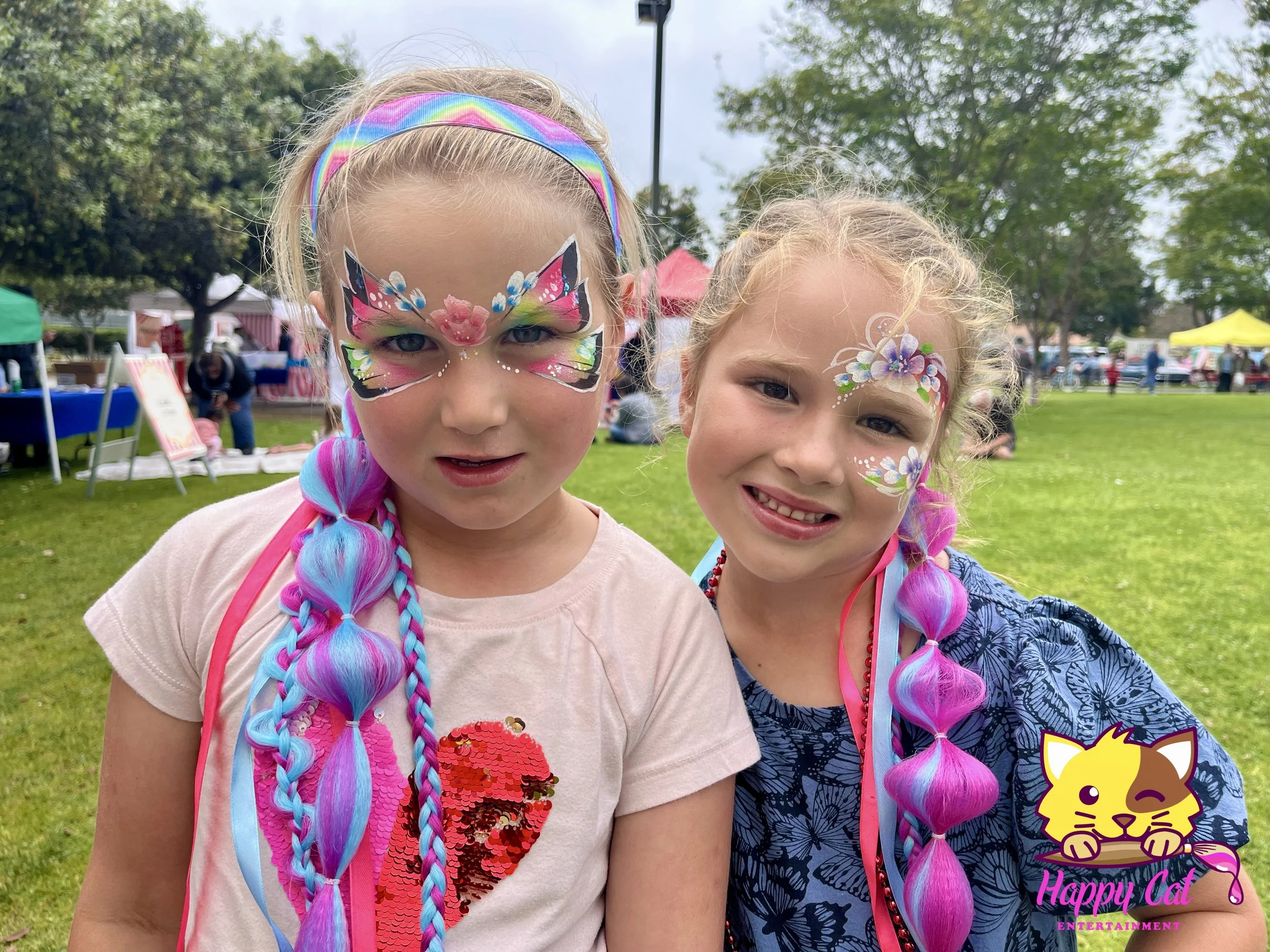 Two girls smiling with colorful face painting by Happy Cat Entertainment