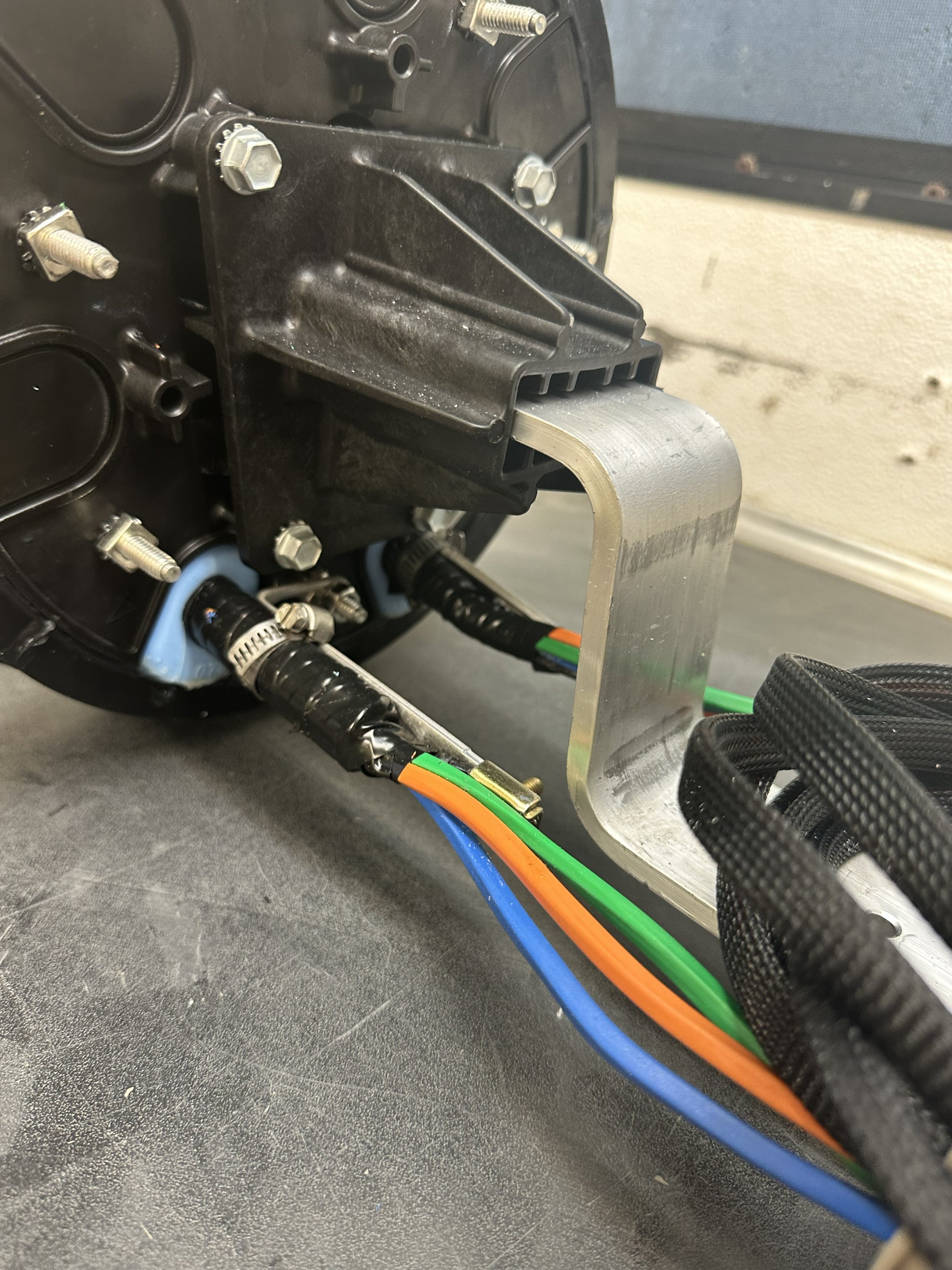 Close-up of an electronic component with cables connected, mounted on a metallic bracket.