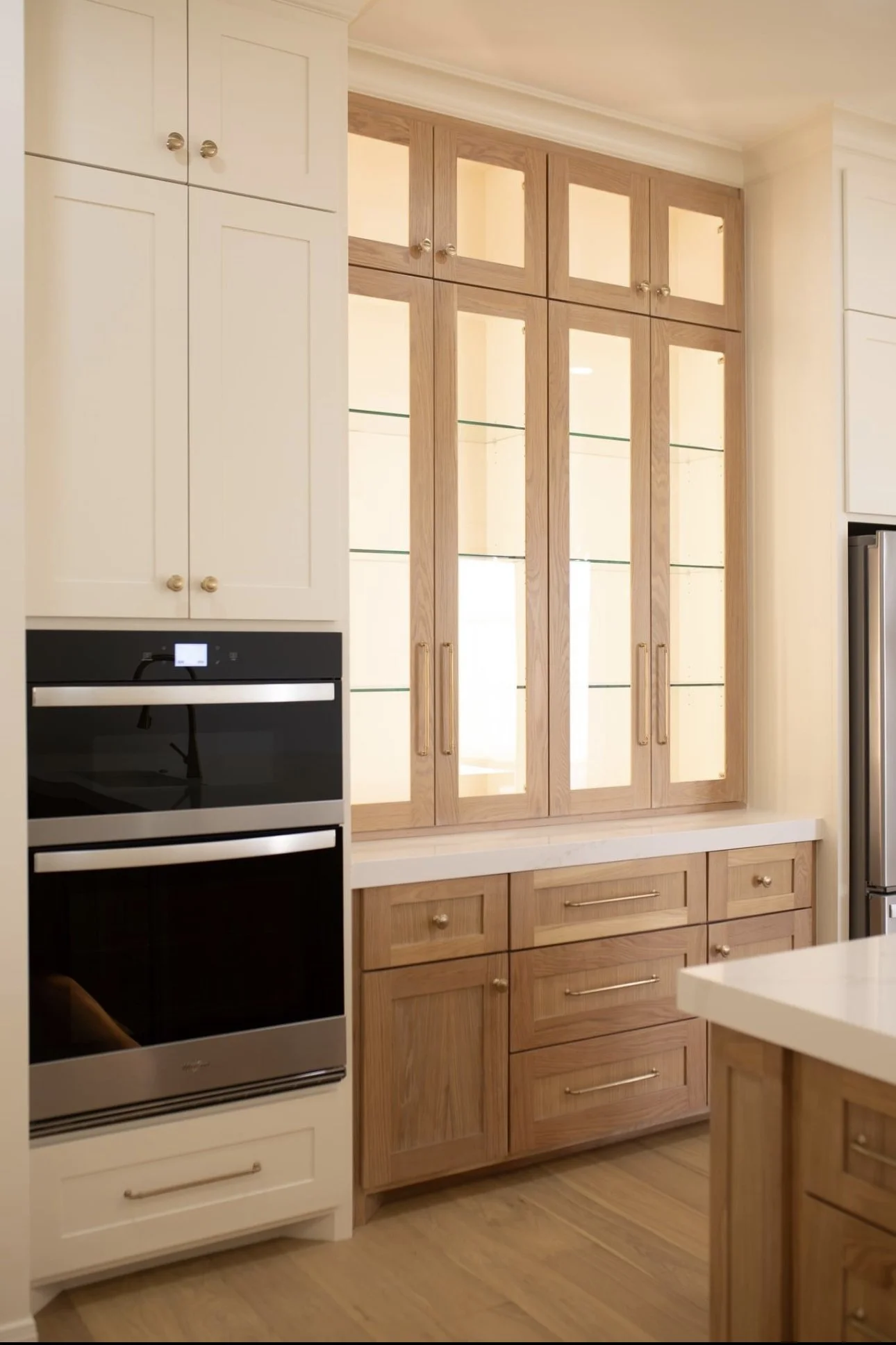 Kitchen with white cabinets, wooden display cabinet with glass doors, and a built-in oven.