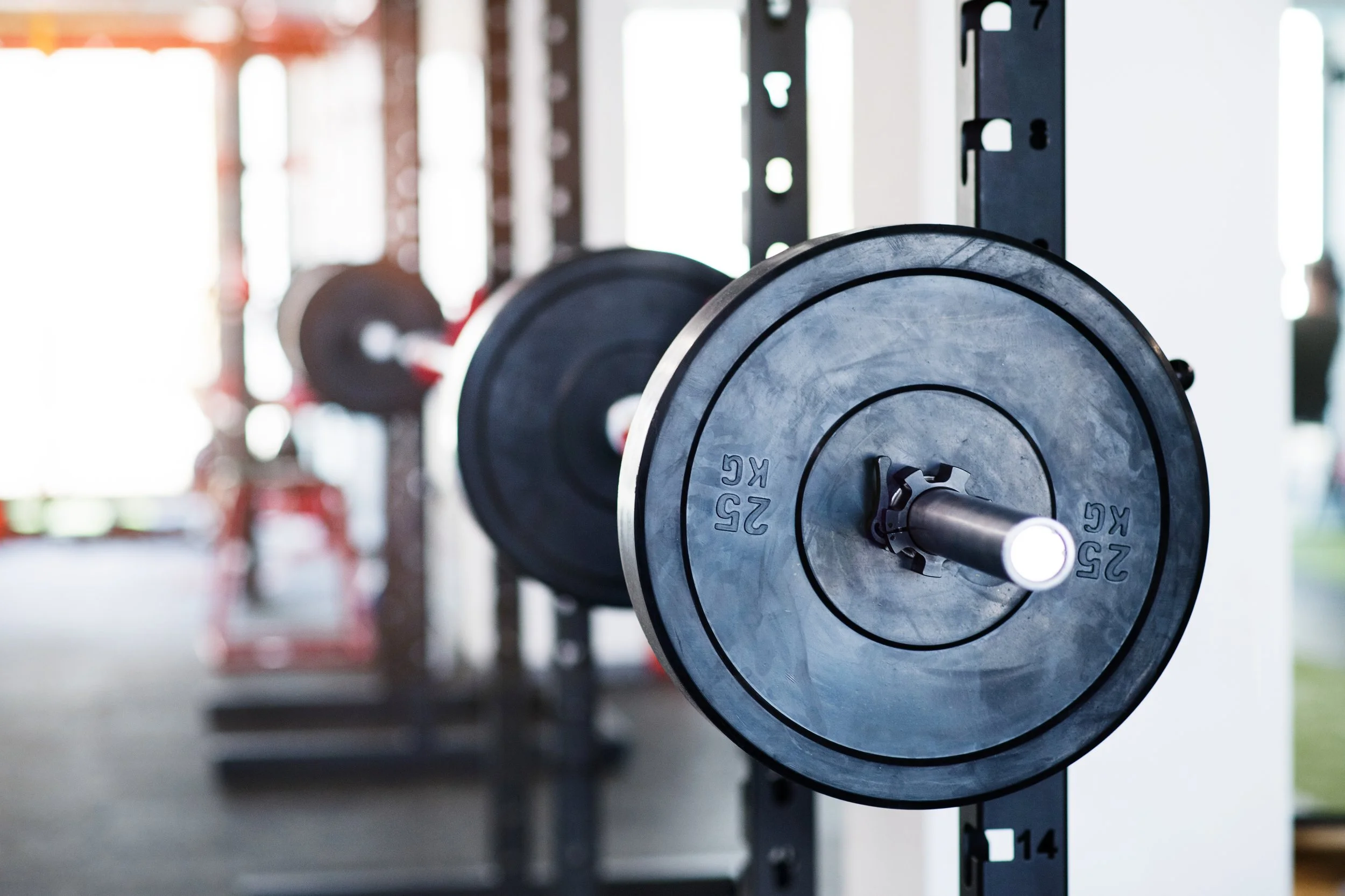 Close-up of black weight plates on a weightlifting barbell in a gym.