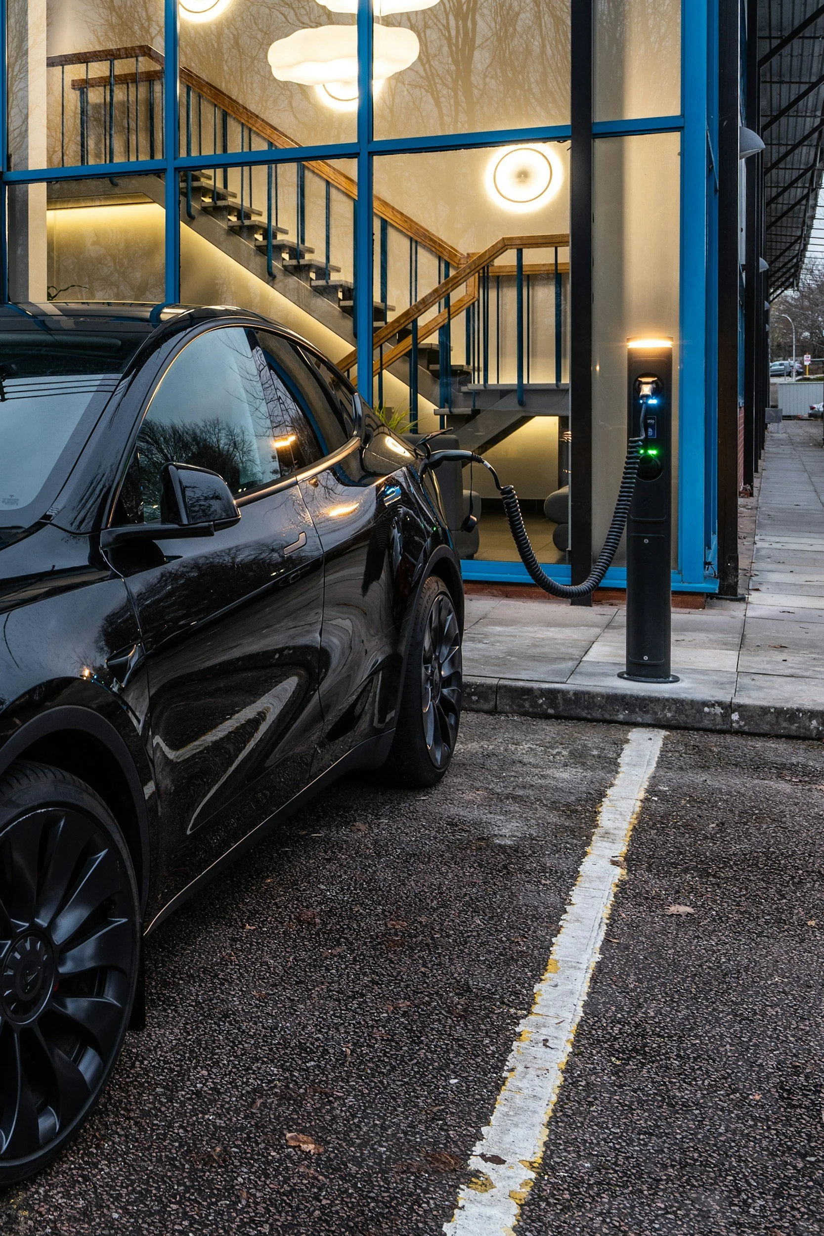 Electric vehicle charging at a parking lot with a building visible in the background