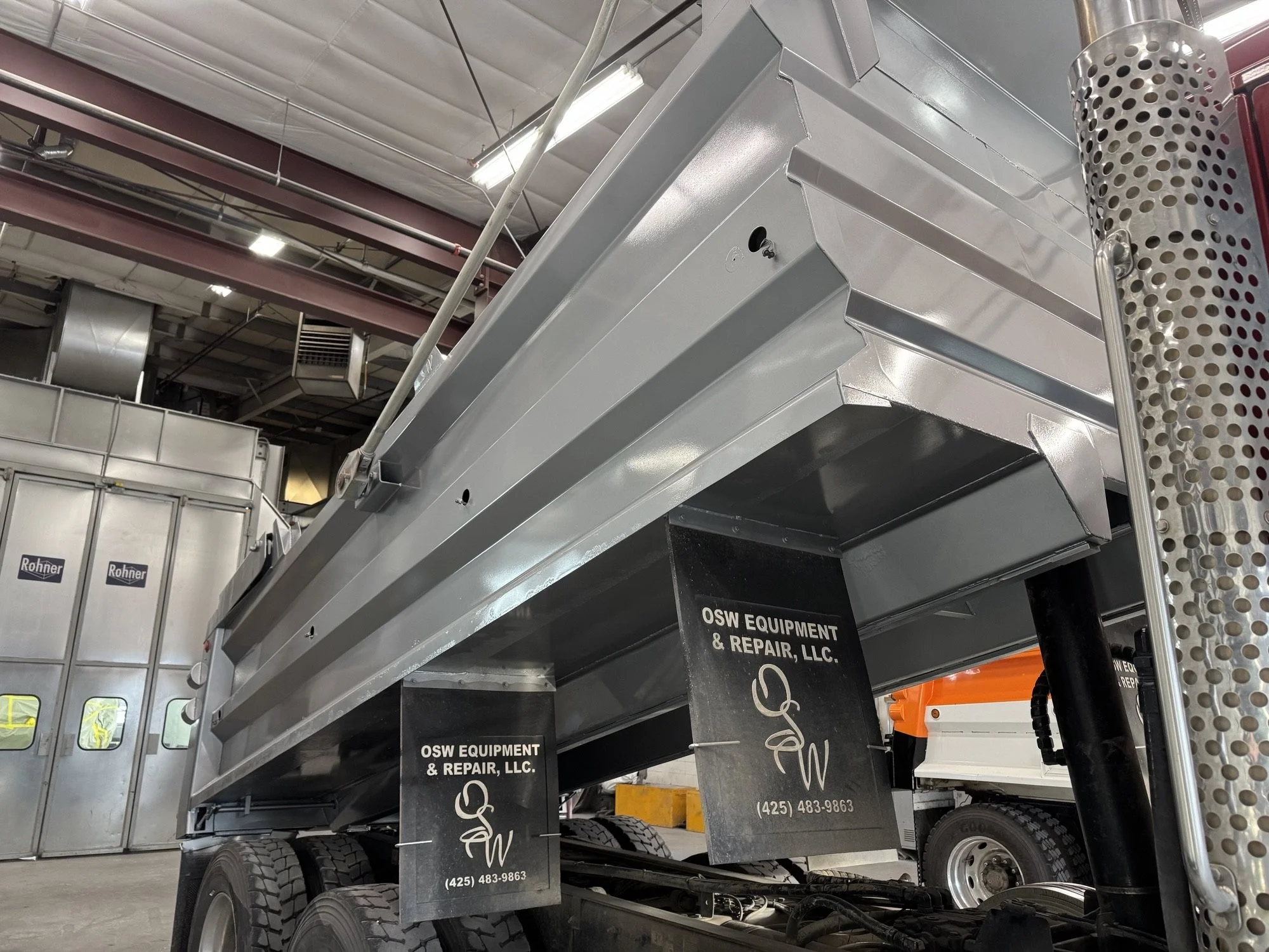 A freshly repaired large industrial dump truck bed inside Heiser Body warehouse. 
