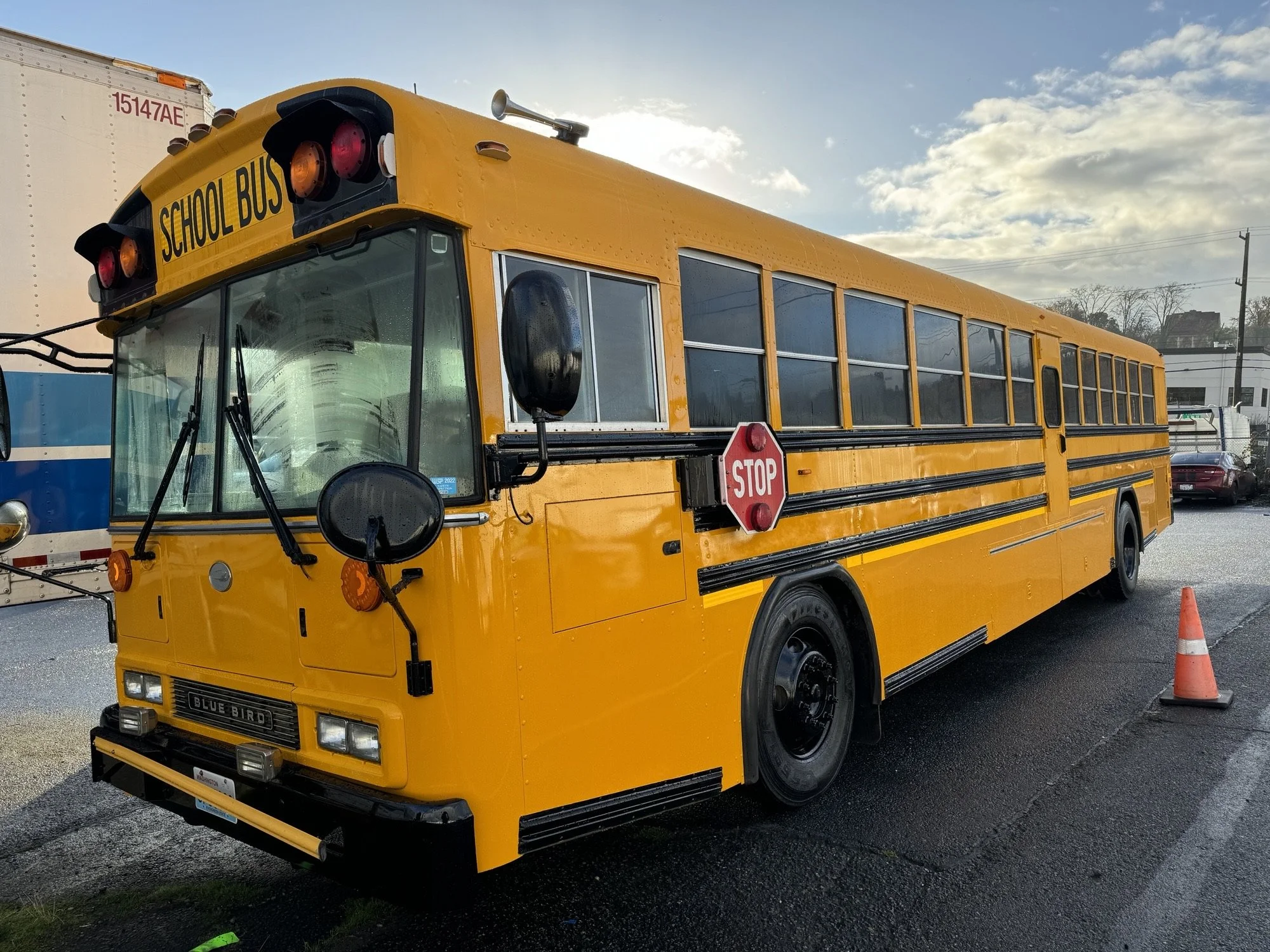 A freshly painted yellow school bus parked outside on a cloudy day.