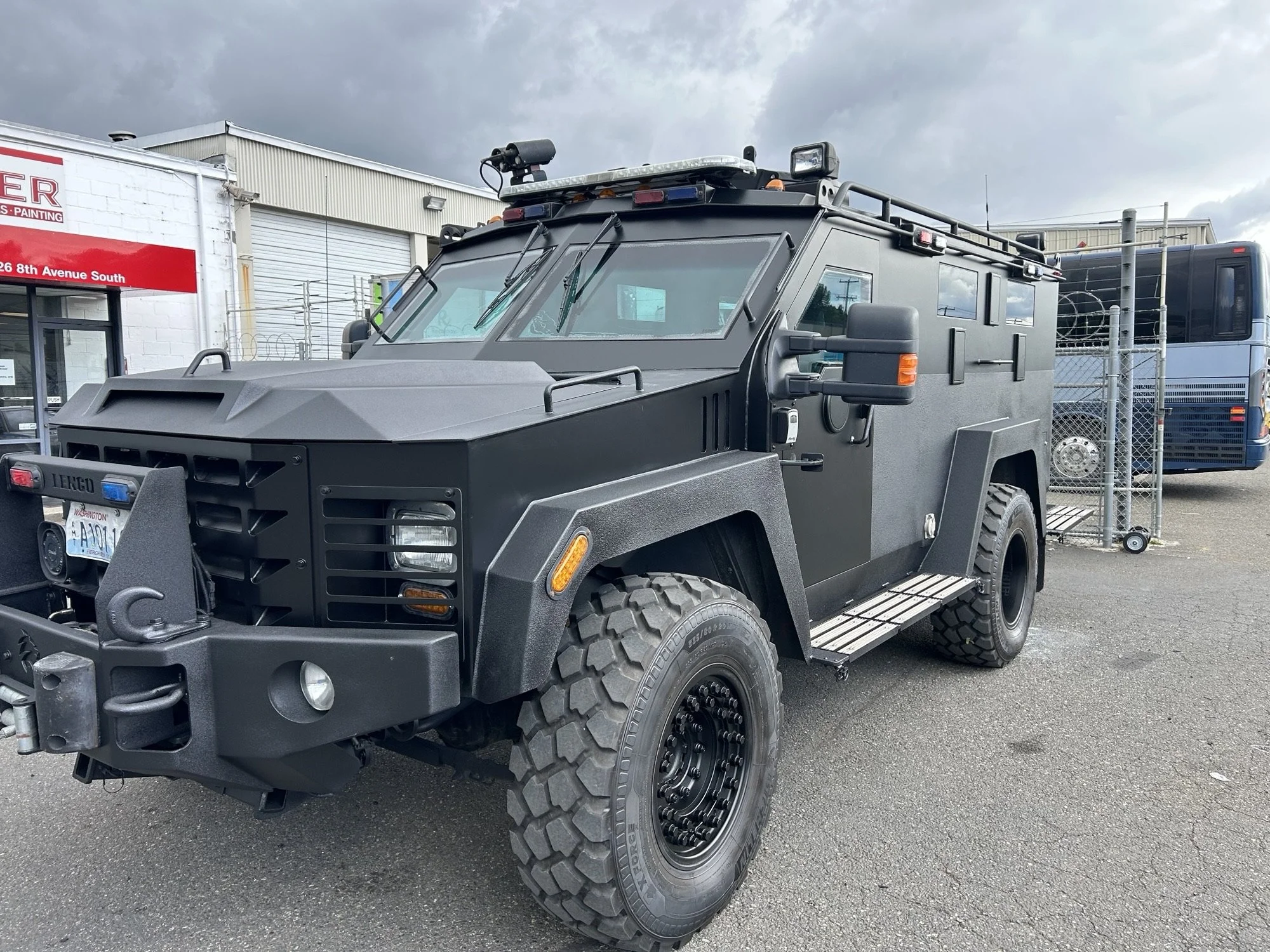 A freshly painted black armored tactical truck, parked outdoors near a building.