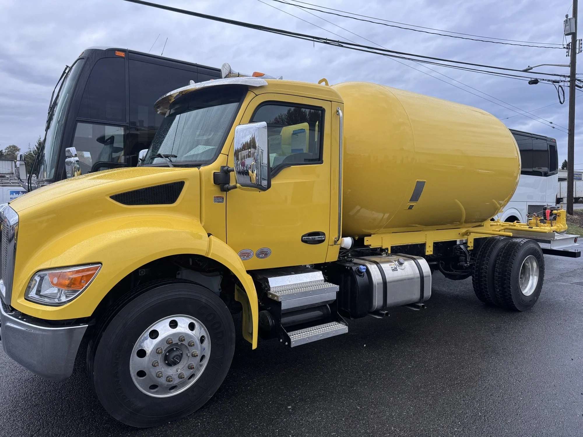 Yellow water tanker truck parked in the Heiser Body parking lot.