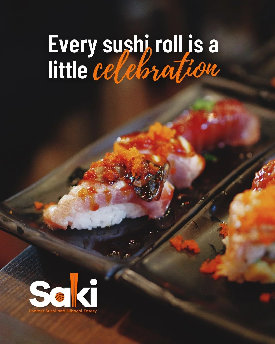 Close-up of sushi rolls topped with orange fish roe and sauce on a black rectangular plate at a restaurant.