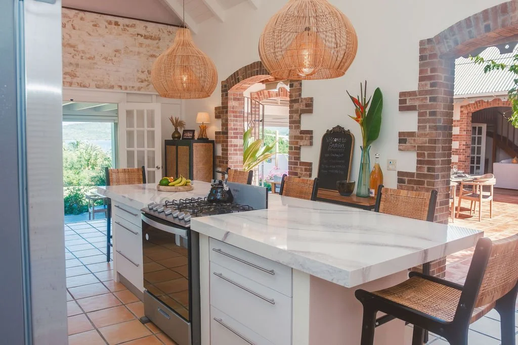 Modern kitchen with white marble island, brick accents, and rattan pendant lights.