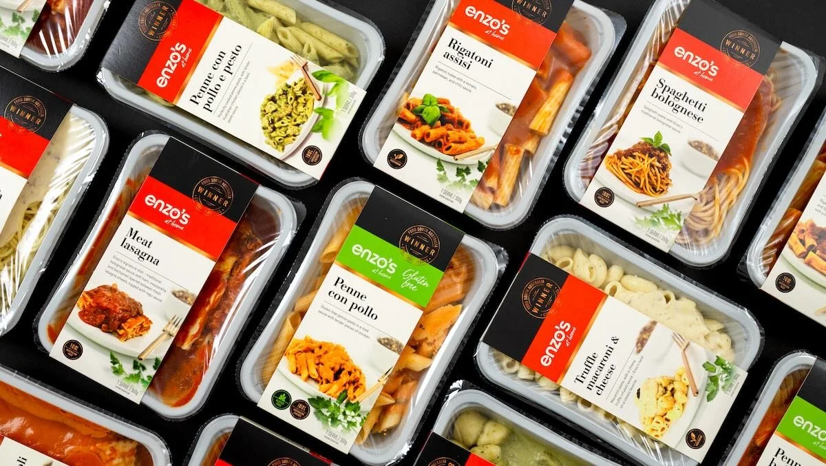 Packets of pre-packaged Italian frozen meals, including penne with pesto, rigatoni, spaghetti bolognese, meat lasagna, penne with chicken, and tortellini macaroni and cheese, labeled with the Enzo's at Home brand.
