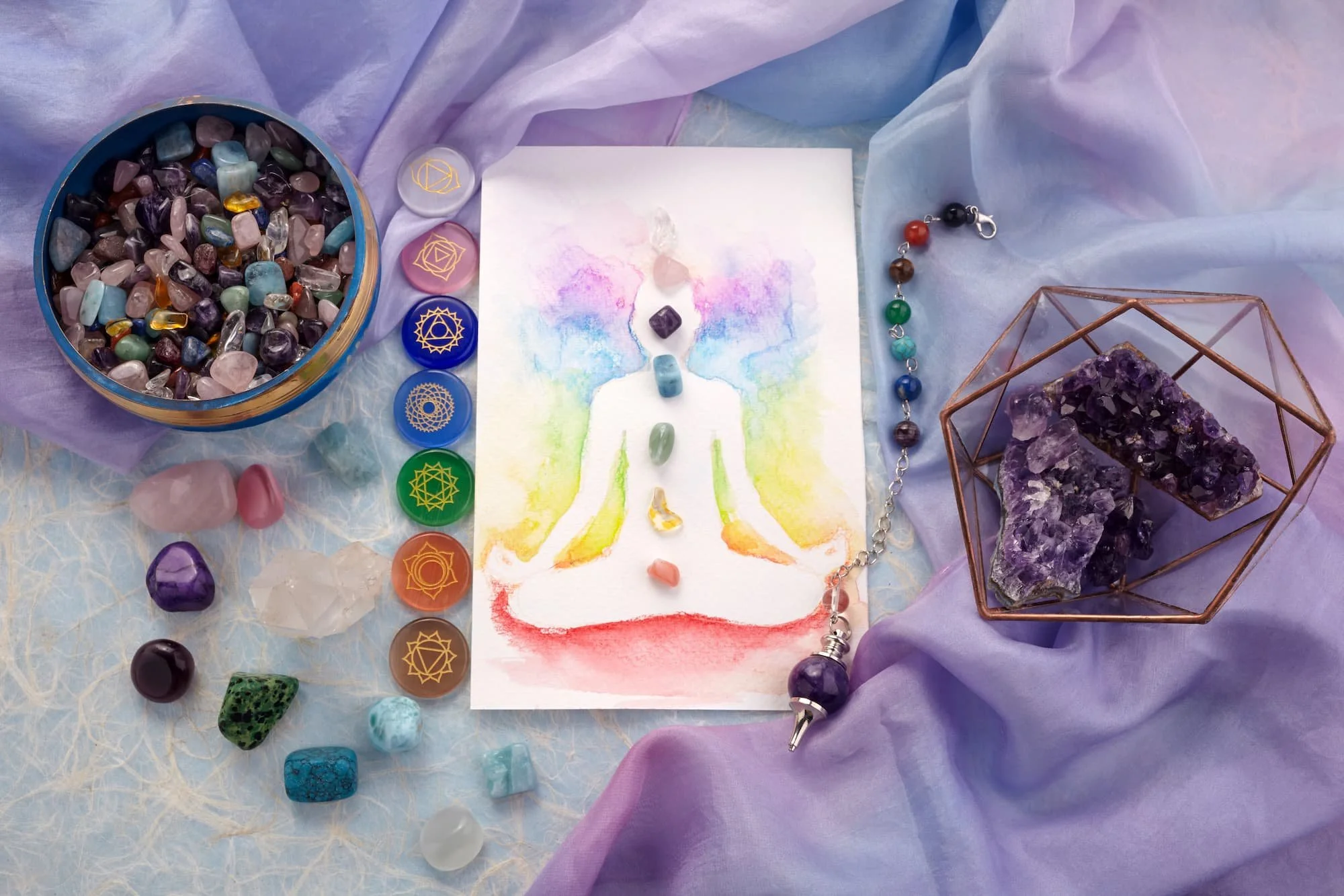 A completed meditation poster with colorful watercolor background of a person sitting in a lotus pose, surrounded by various crystals, gemstones, and spiritual items including a chakra bracelet, amethyst geode, and chakra symbols in a decorative display.