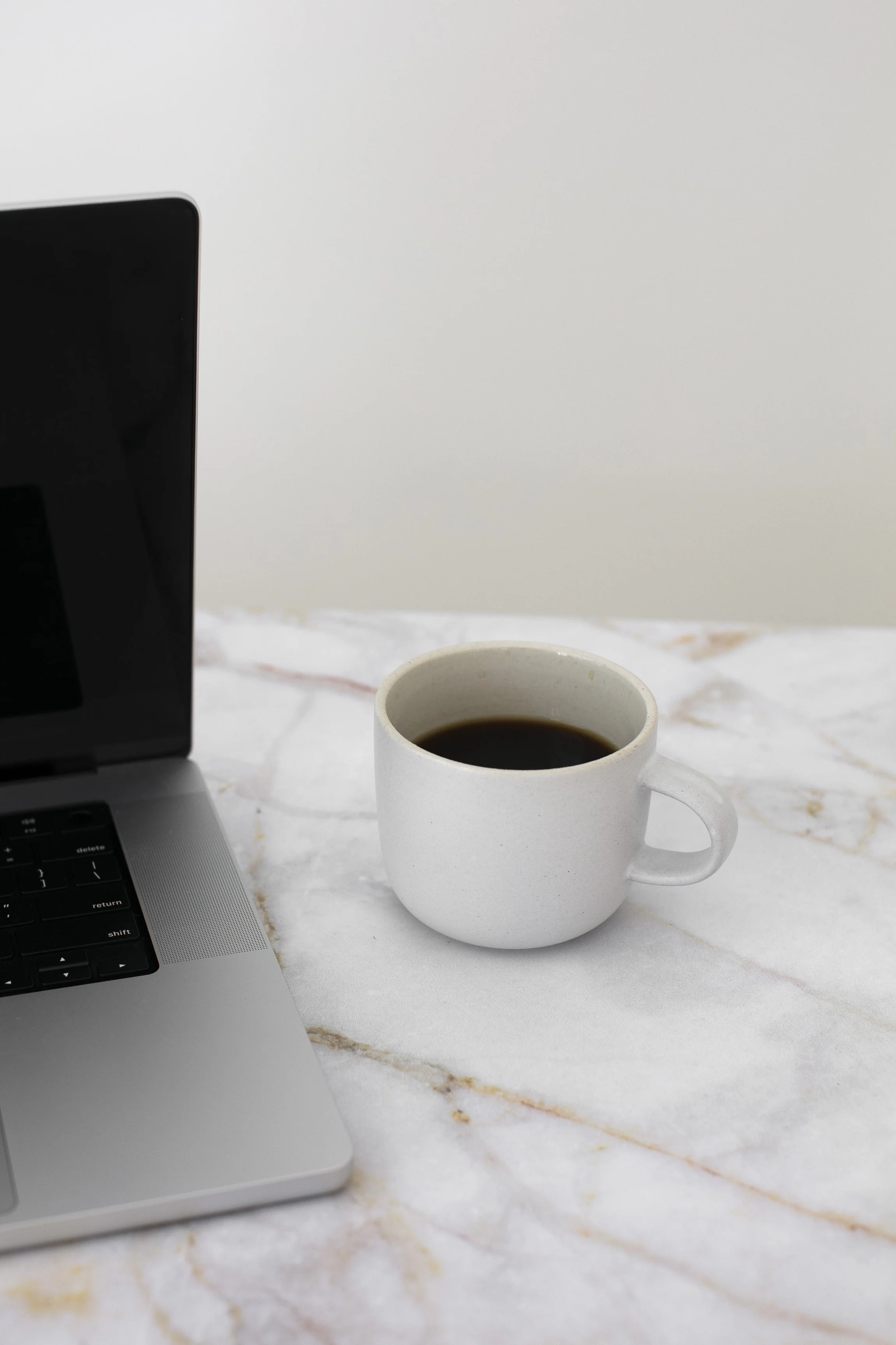 laptop and coffee on a marble desk, photography website design and SEO strategy workspace