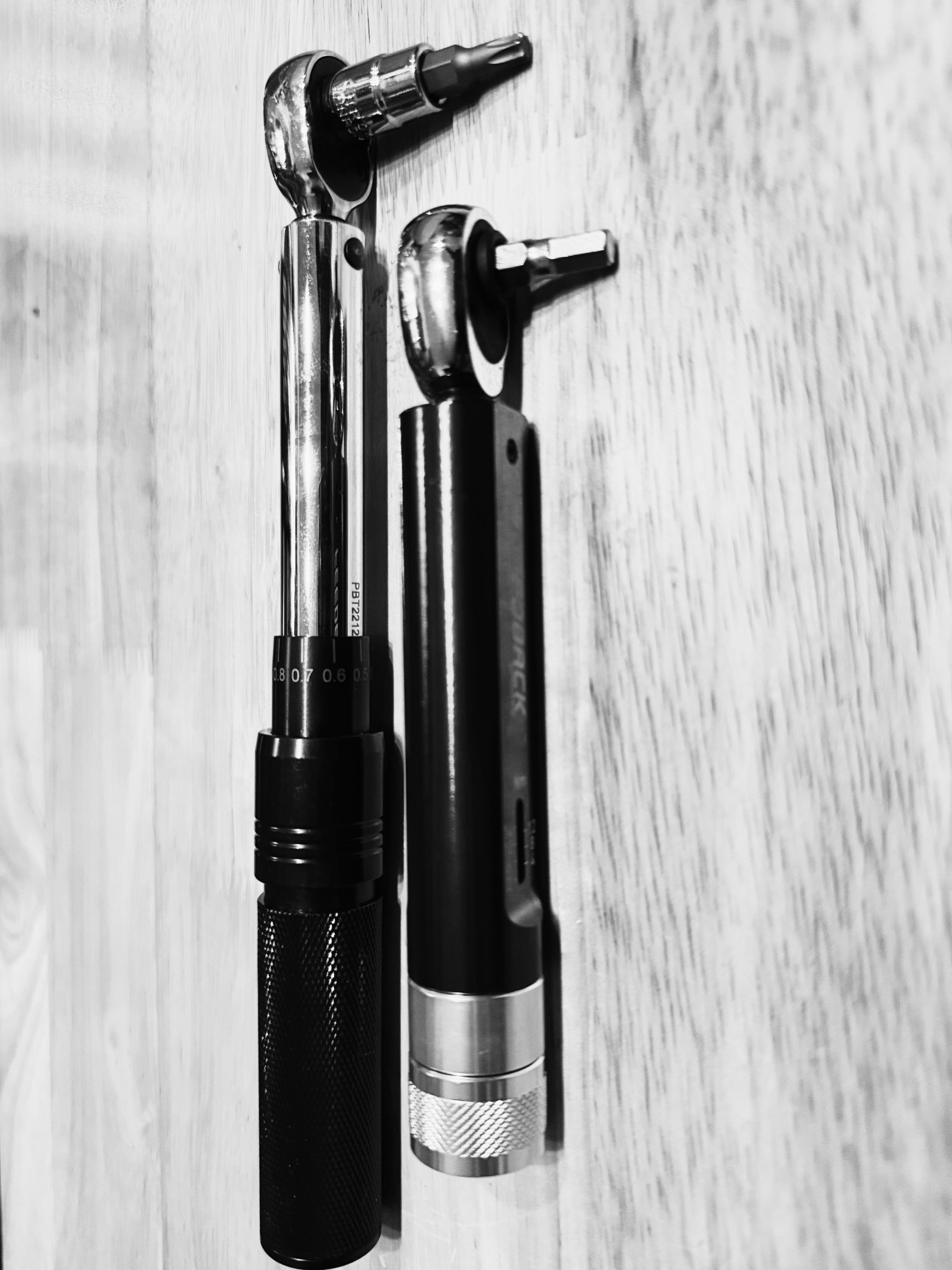 Black and silver infrared thermometers placed on a light wooden surface.