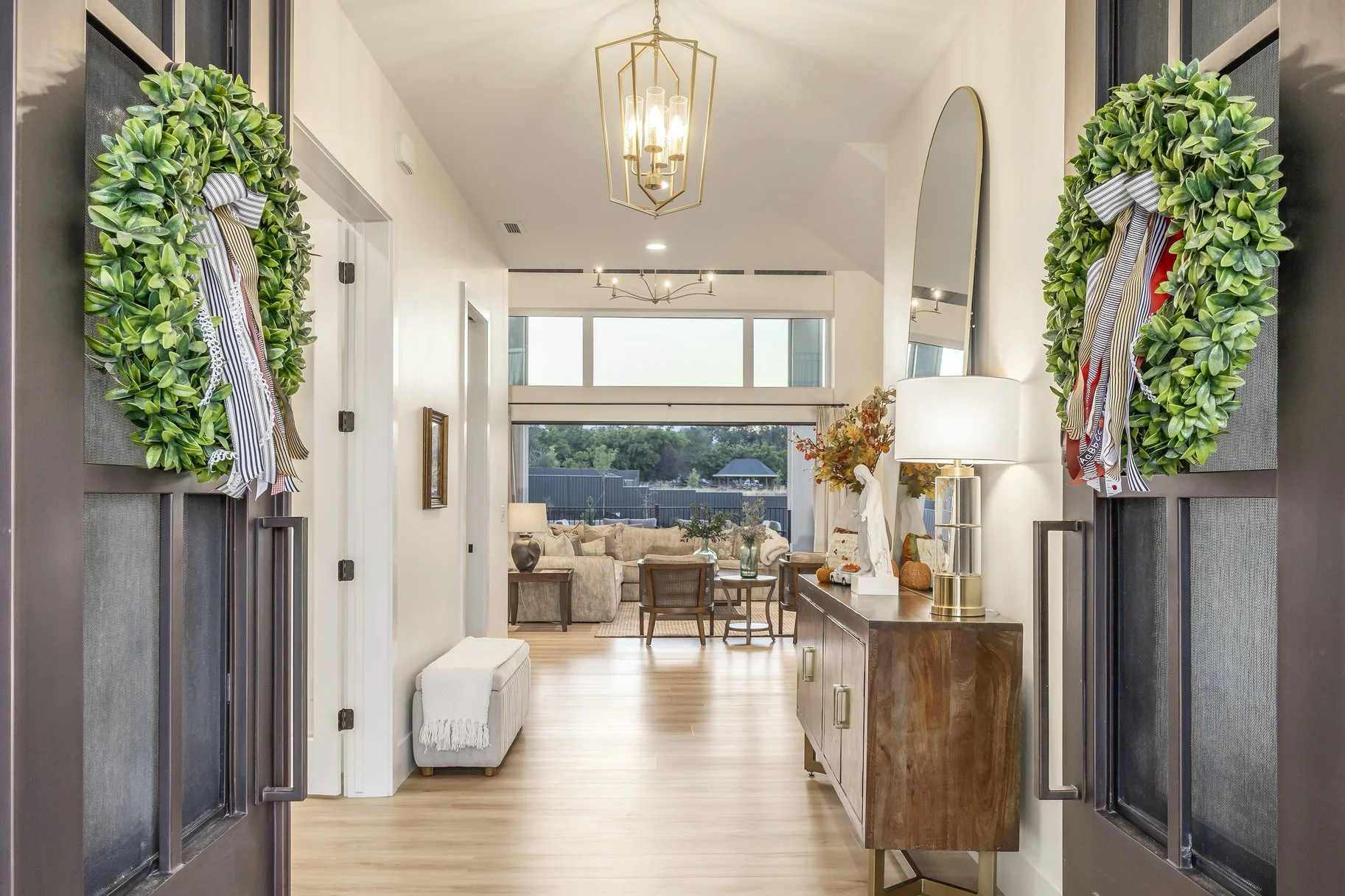 View of a modern living room seen from the entrance hallway, decorated with plants and warm lighting.