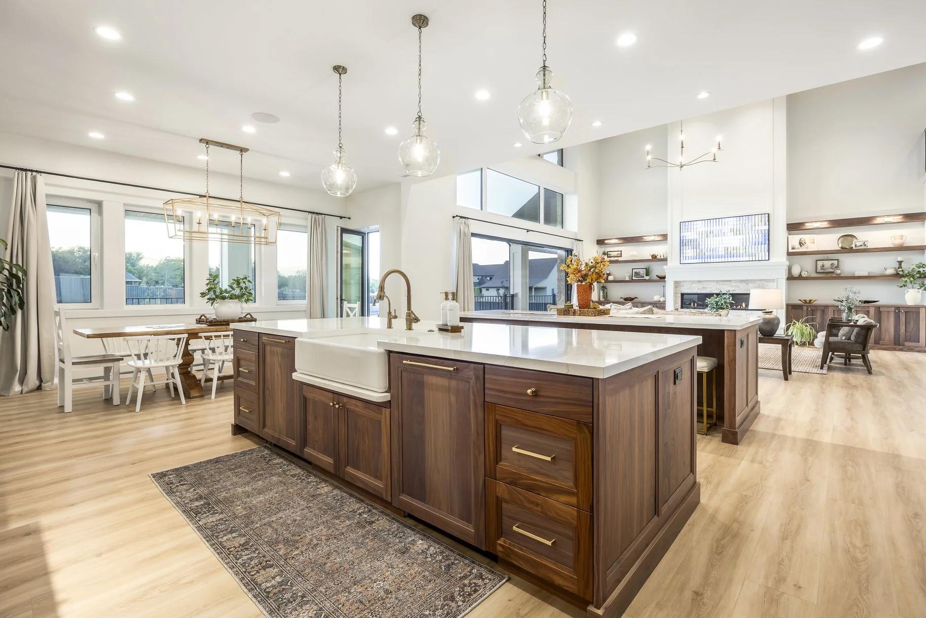 Spacious open-concept kitchen and living area with a large kitchen island, wooden cabinetry, and ample natural light from multiple windows and glass doors.