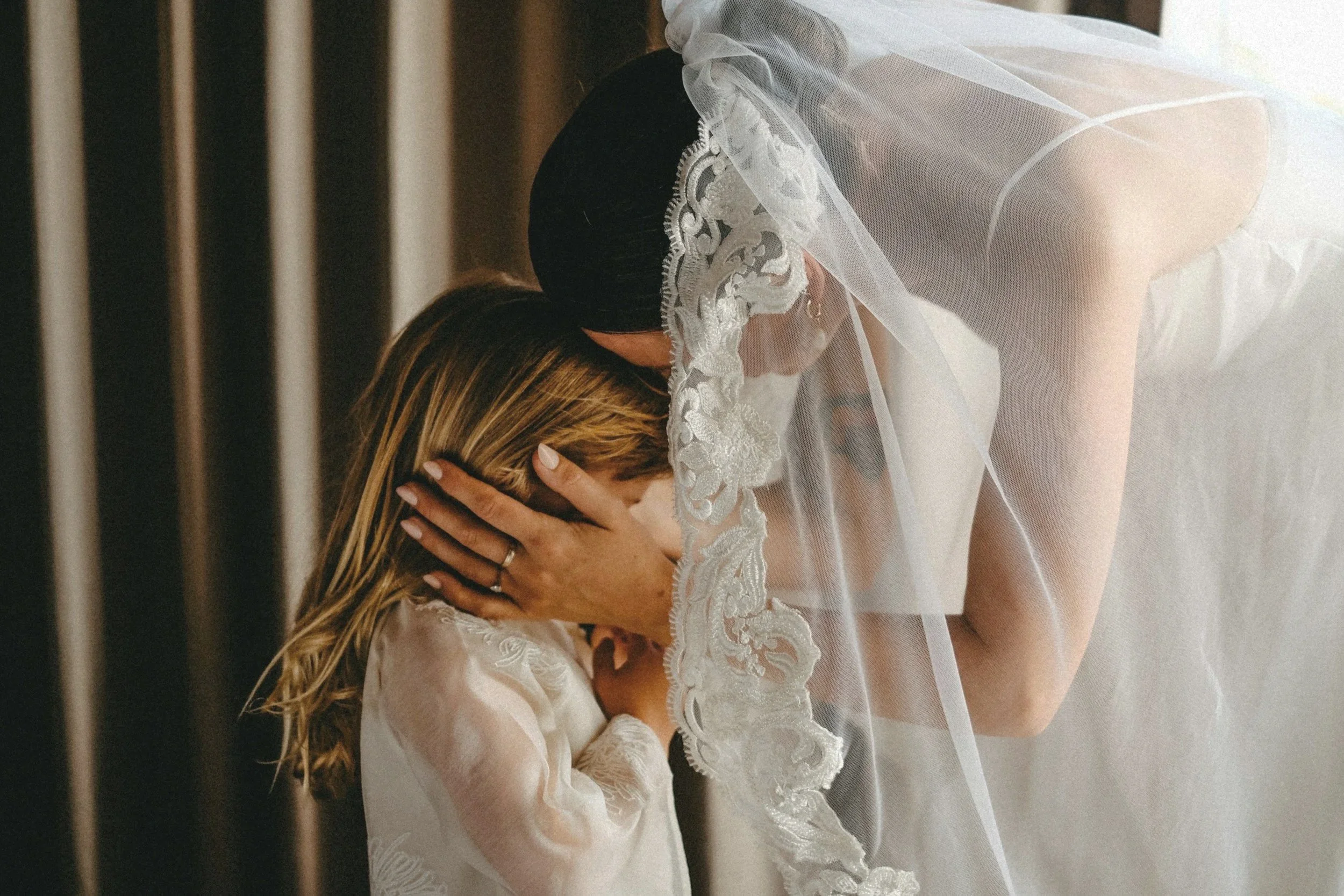 Bride in wedding dress and veil having a sweet moment with the flower girl before walking down the aisle