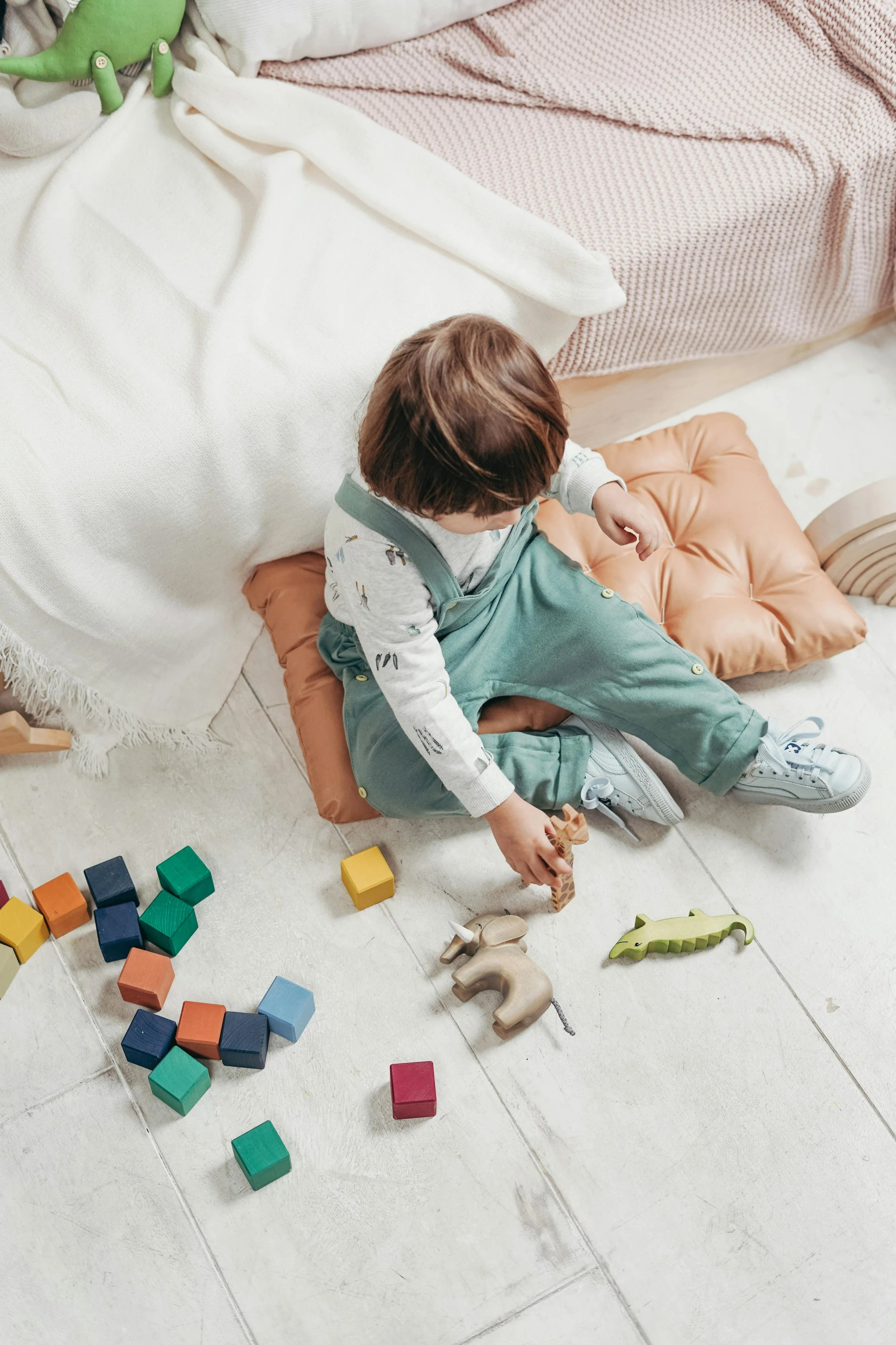 Child sitting on the floor playing with age-appropriate blocks and toys