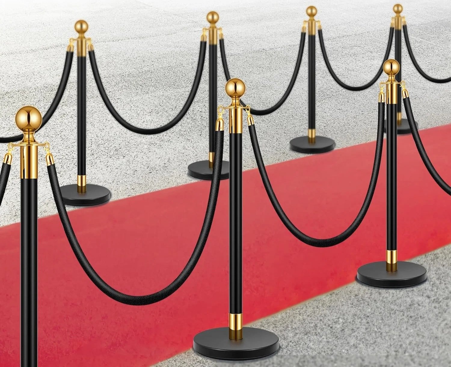 Black stanchions with gold top caps and connecting ropes line a red carpet, creating a walkway.