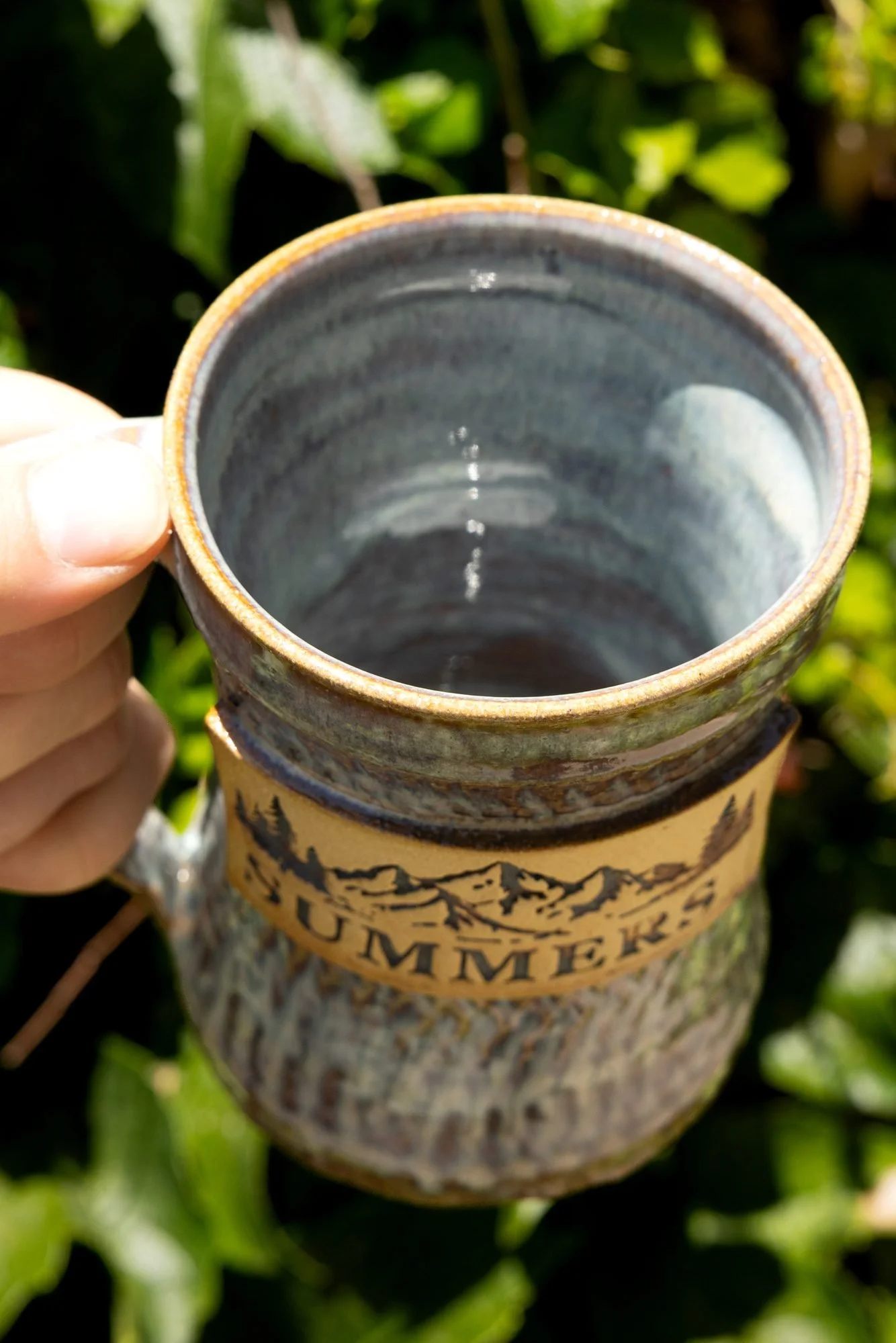 Looking down into a finished blue grey glazed mug showing a smooth glossy interior