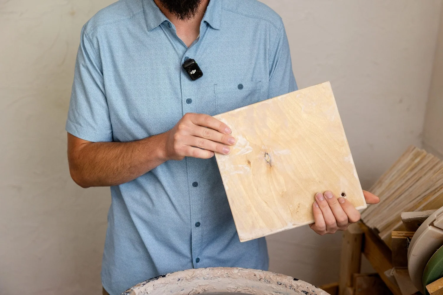 Adam in a blue shirt holding a square wooden bat in front of his wheel