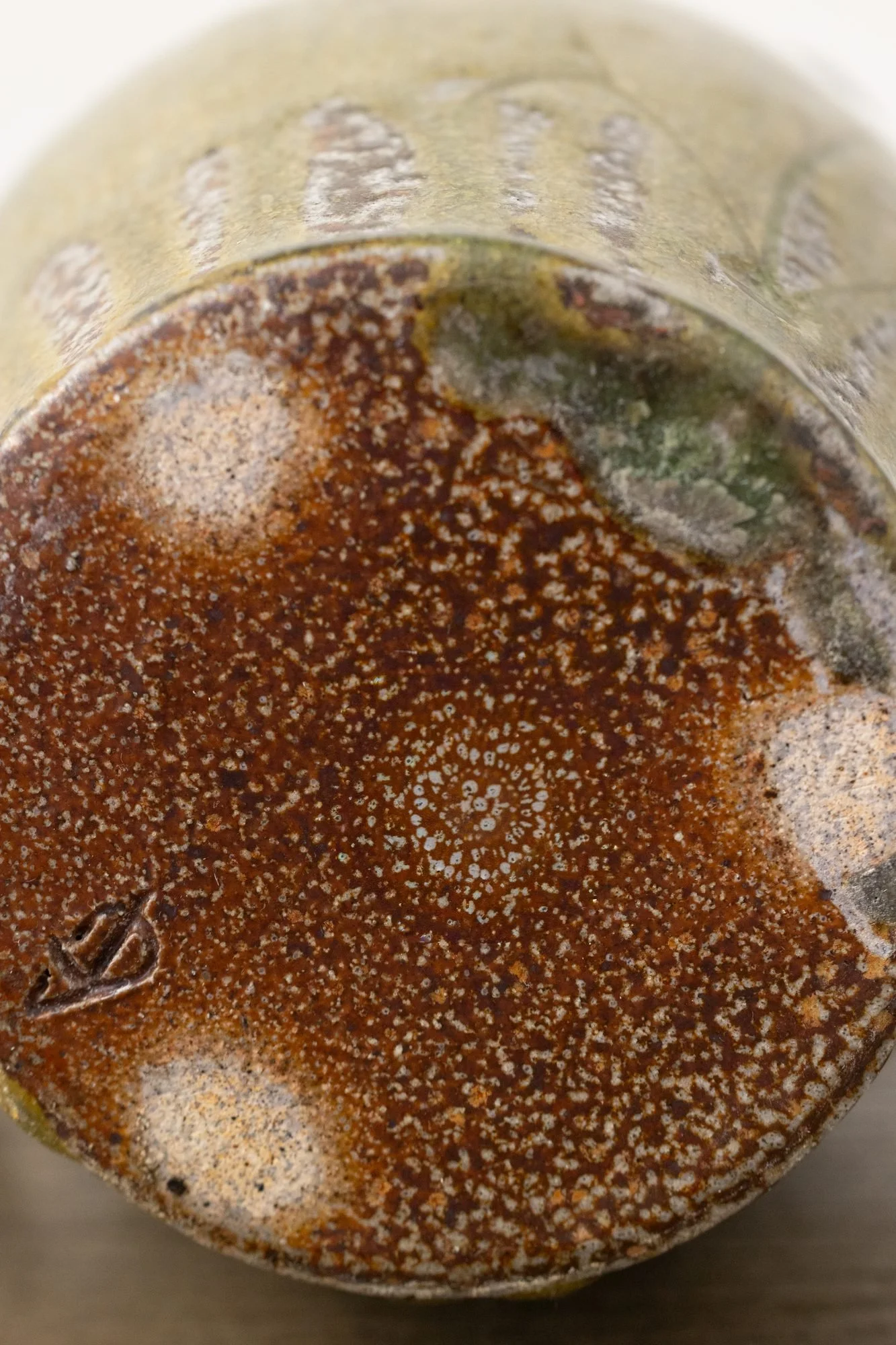 Close view of the warm orange foot of a pot with pale round marks where wadding sat