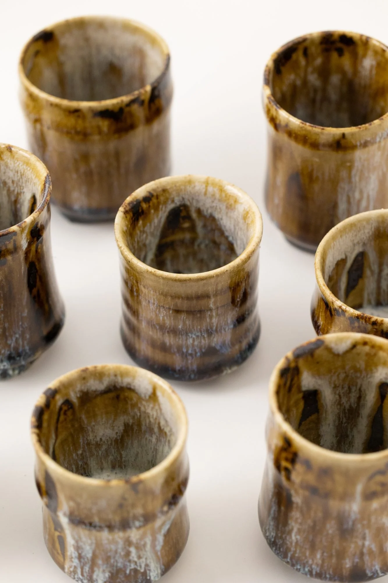 A group of small glazed cups with amber and white runs, seen from above