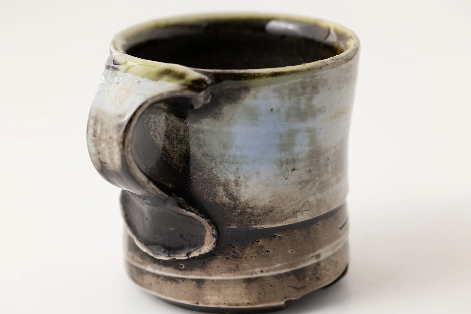 A cylindrical mug with gray, black and pale blue flashing and a dark handle, on a white background