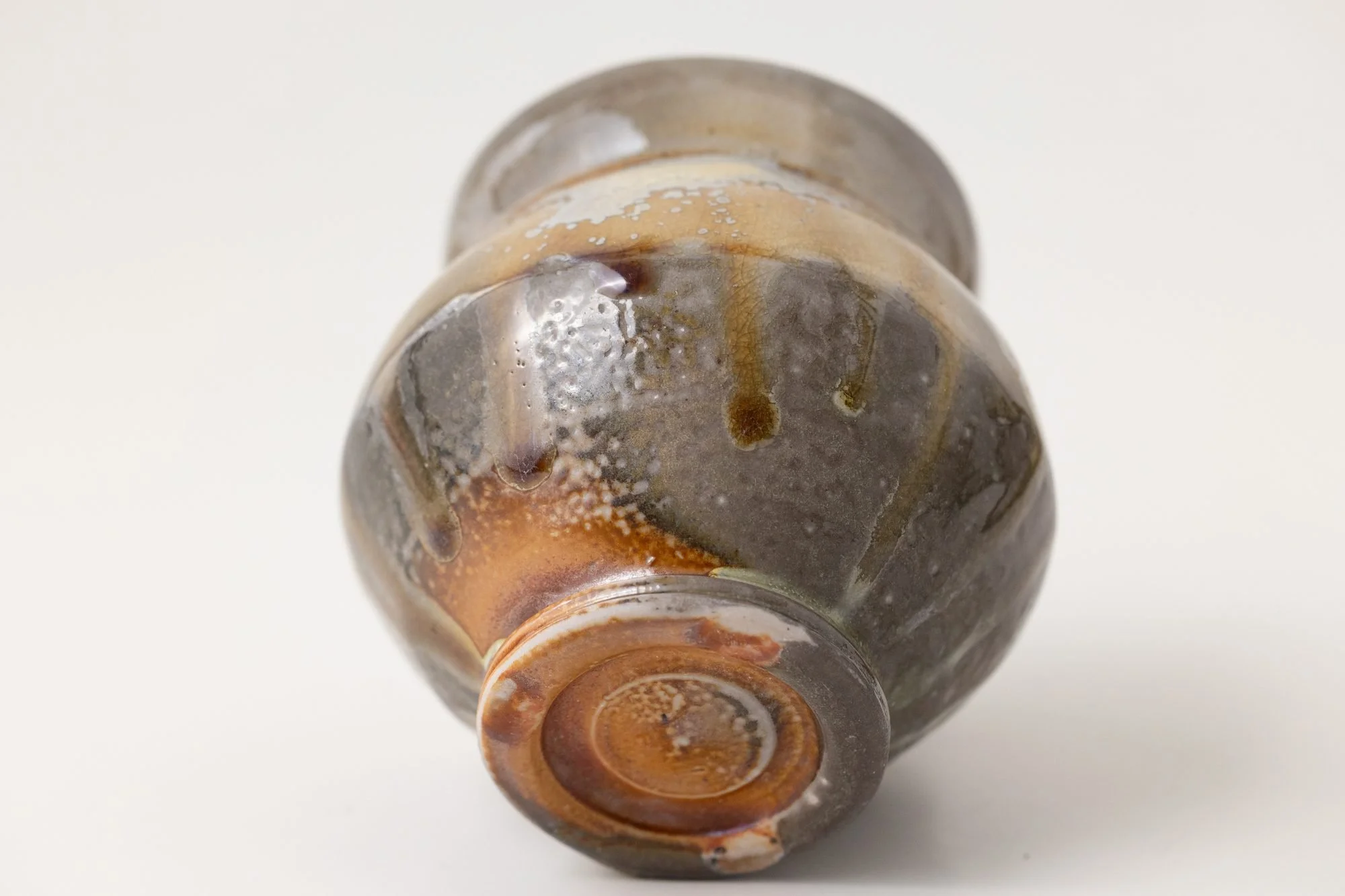 A round pot tipped on its side to show a warm orange foot ring
