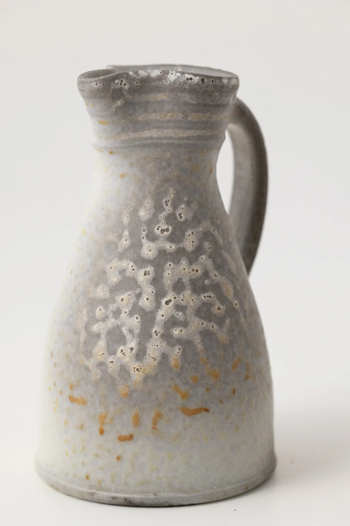A pale gray pitcher with a soft speckled surface on a white background