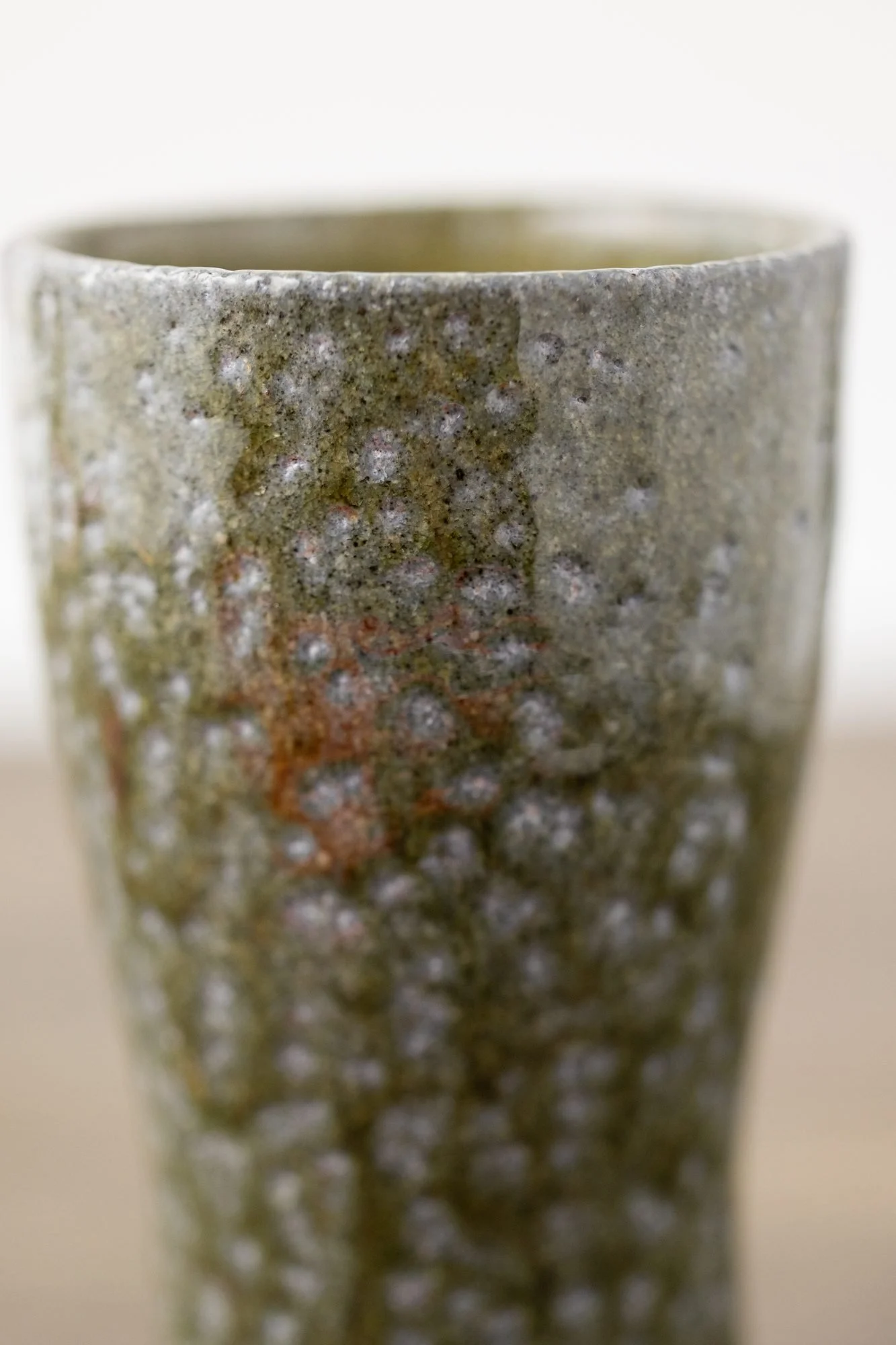 Close view of a tumbler with a speckled green and orange textured surface