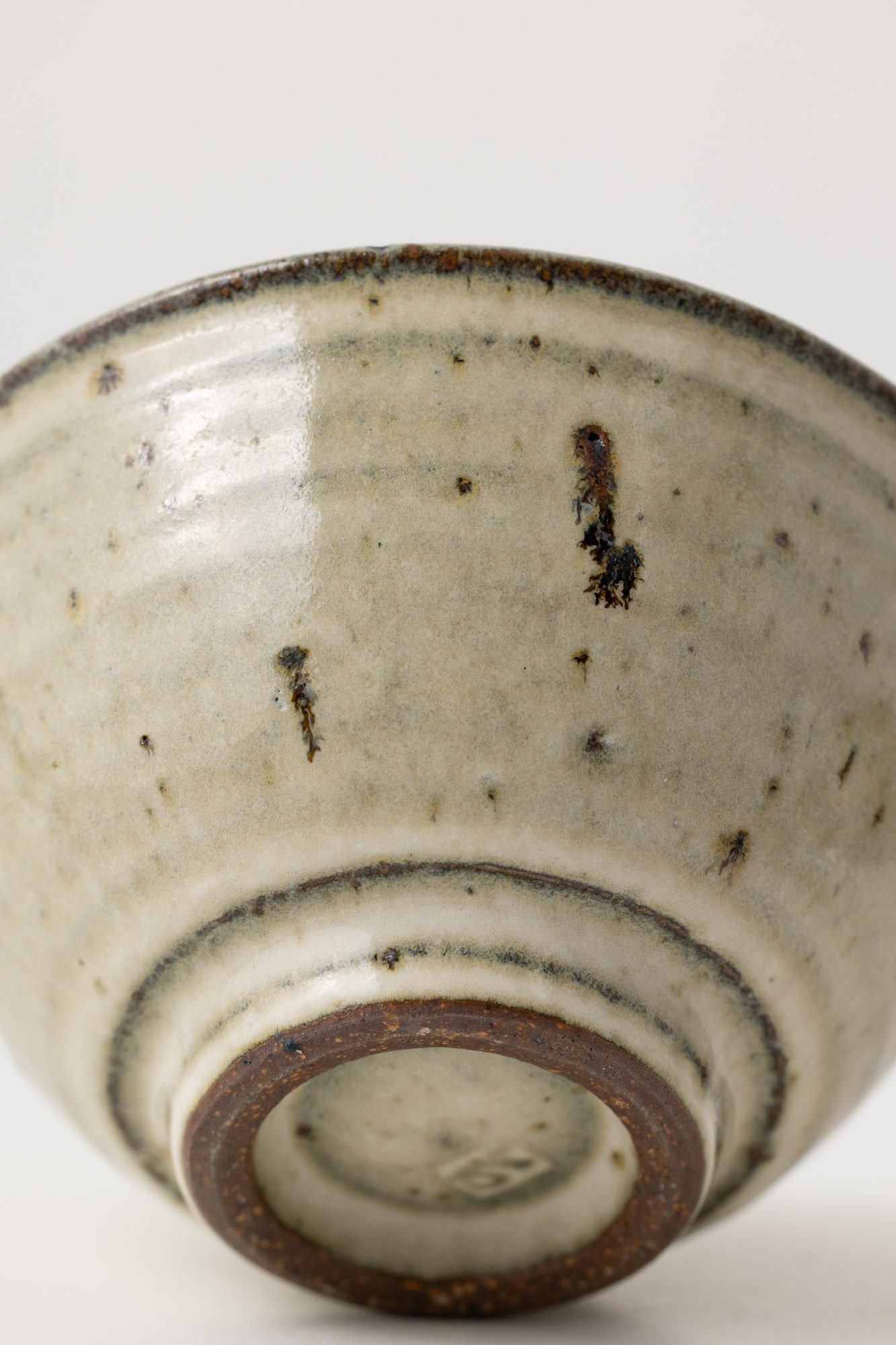 Close view of the underside of a speckled bowl showing its trimmed foot ring