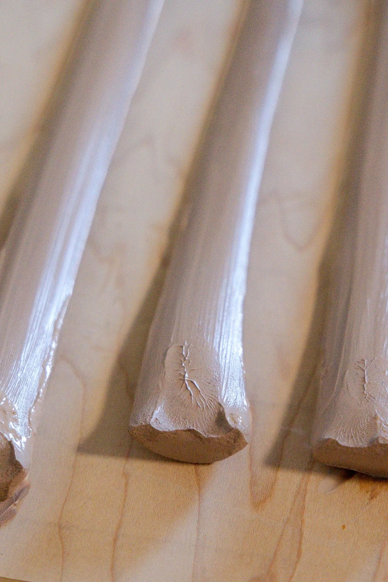 Several pulled clay handles resting on a wooden board