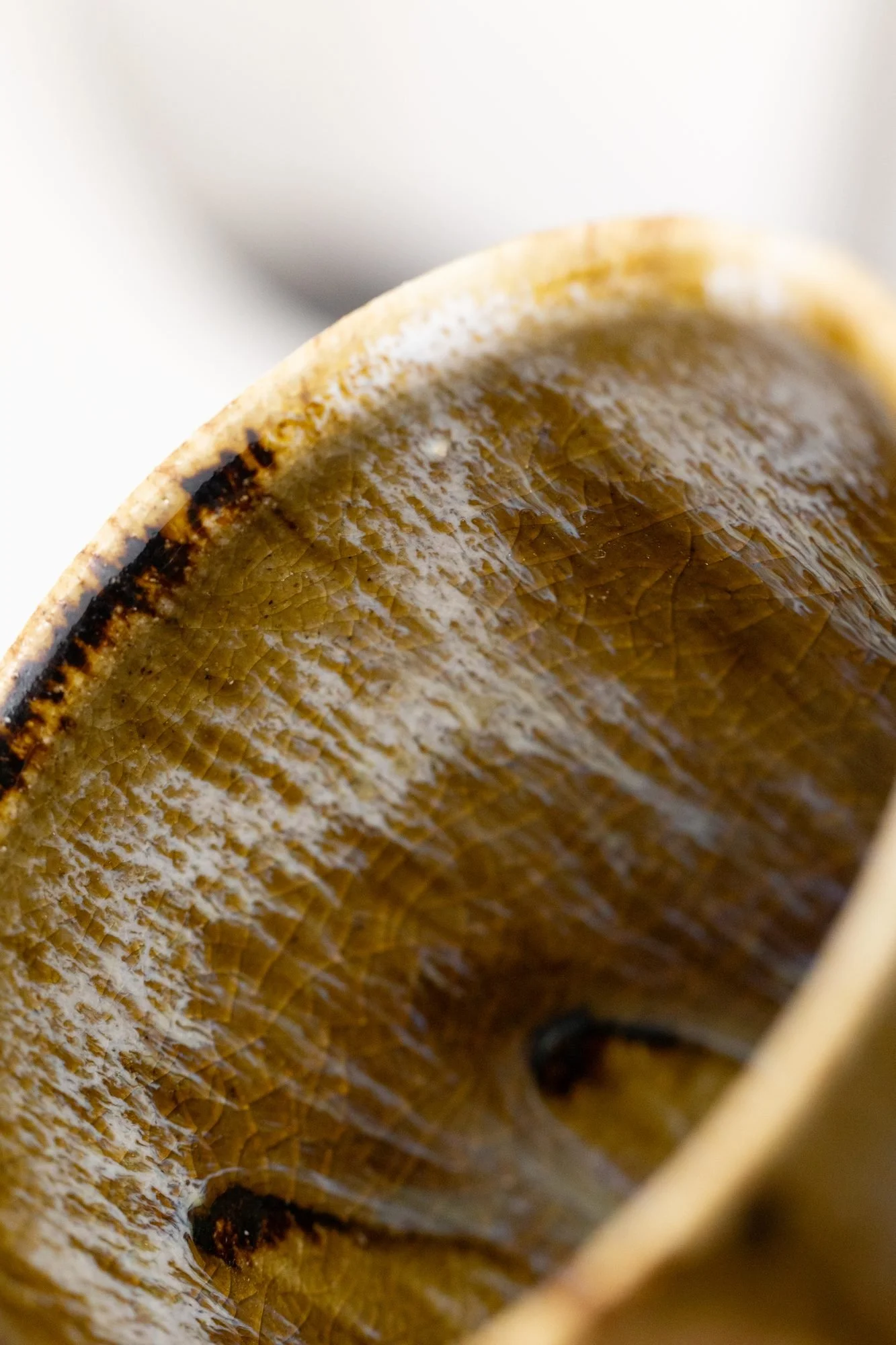 Close view inside a glazed cup showing a smooth, glossy amber and white surface