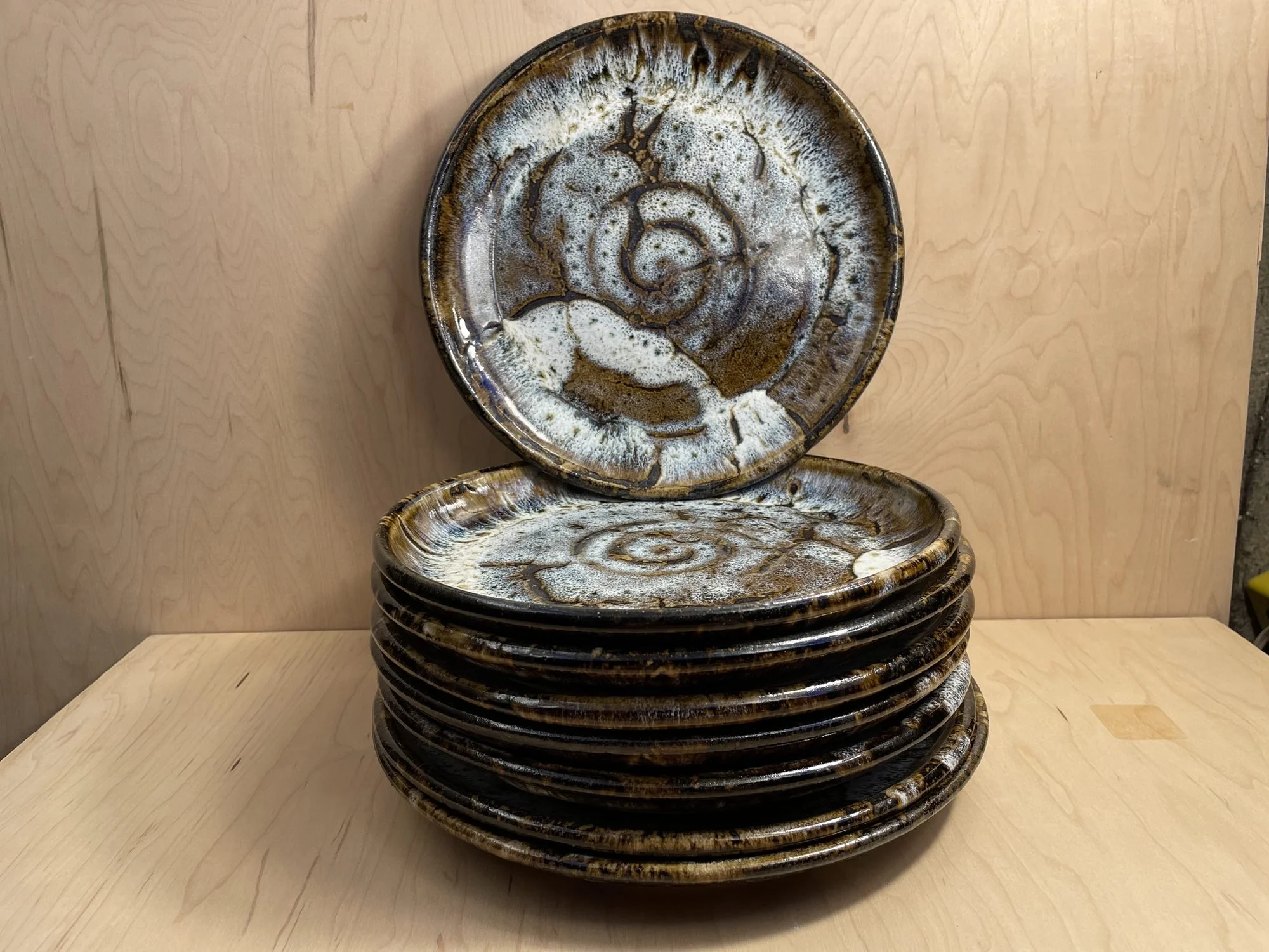 A stack of glazed plates with one standing upright behind, showing a white spiral center