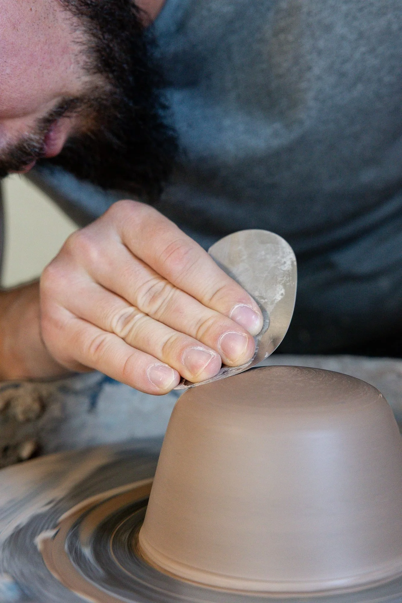 Adam trimming an upside down leather hard bowl on the wheel with a metal rib