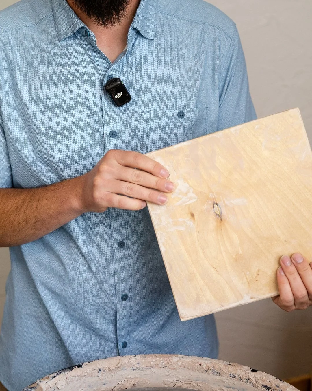 This square of plywood is called a bat, and it's how a wet pot gets off the wheel without getting squished.

It locks onto the wheel head, the pot gets thrown on top of it, and when the pot is done the whole board lifts off with it. Nobody has to pic