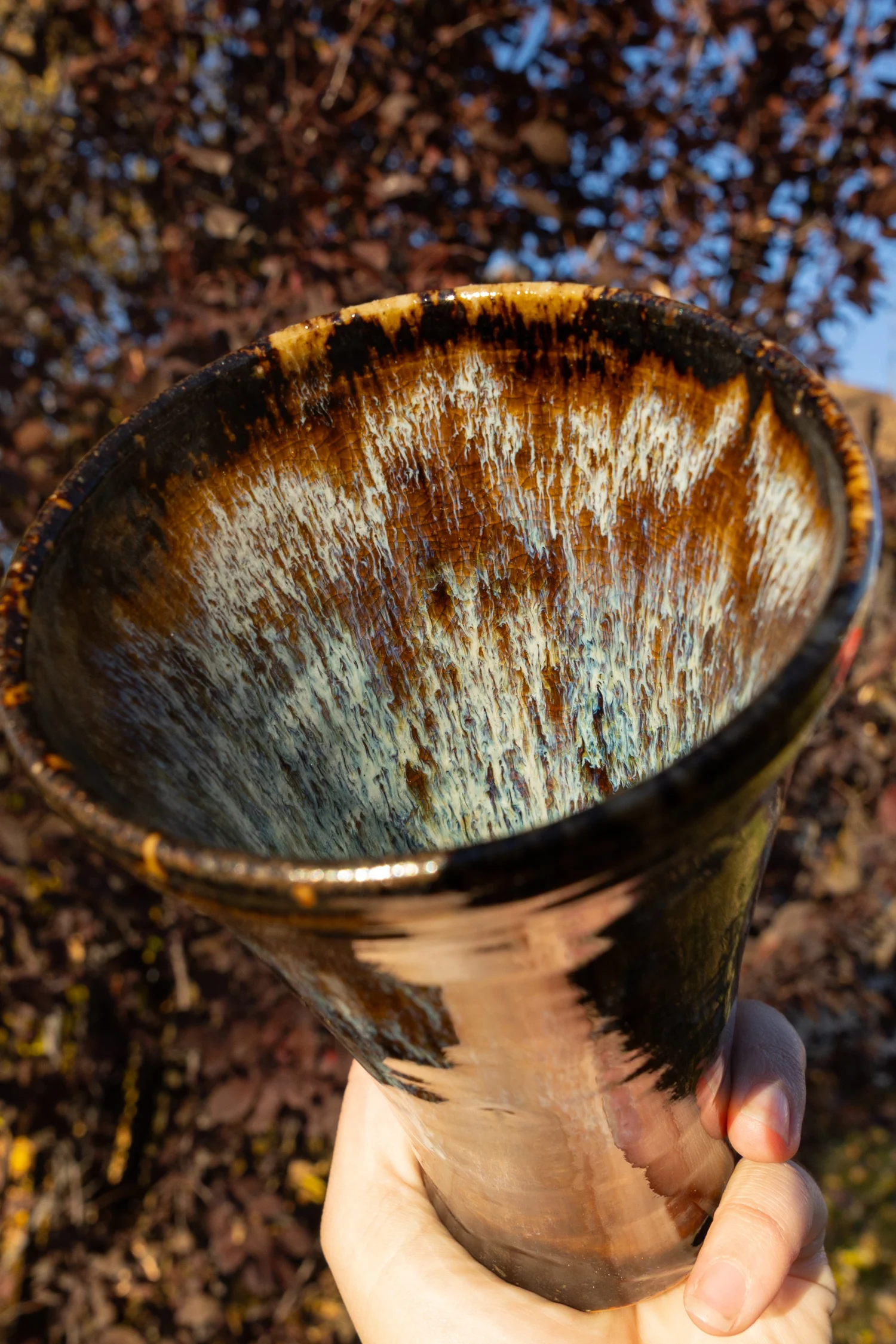 Close-up of a glazed stoneware bowl by Adam Corbridge against fall leaves