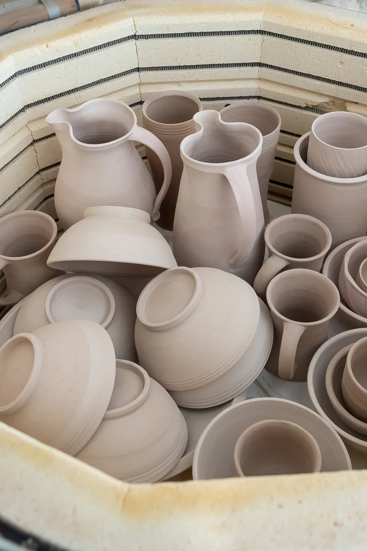 Greenware pots loaded on a kiln shelf before firing