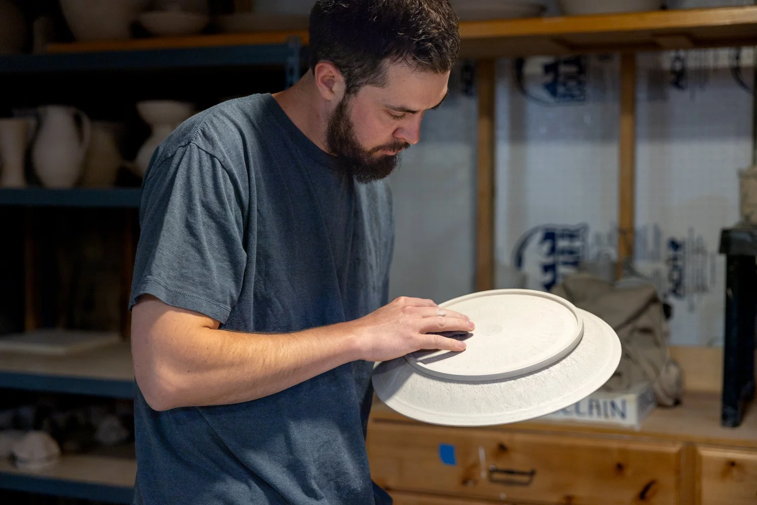 Adam Corbridge inspecting a large carved platter in the studio
