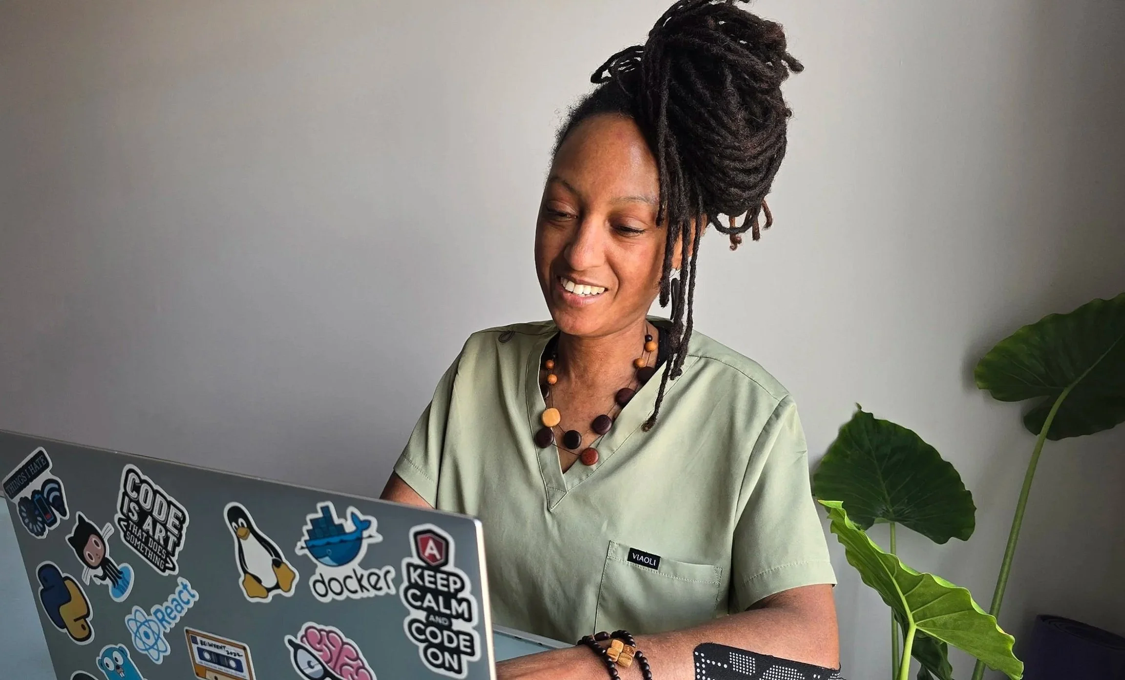 Two people working at a table with notebooks, a glass of water, a laptop, and a vase with two calla lilies.
