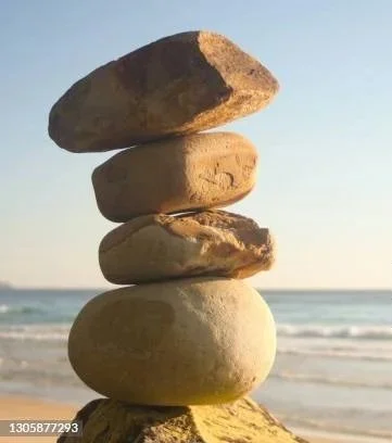 Stacked rocks arranged in a balanced tower on the beach with the ocean in the background.